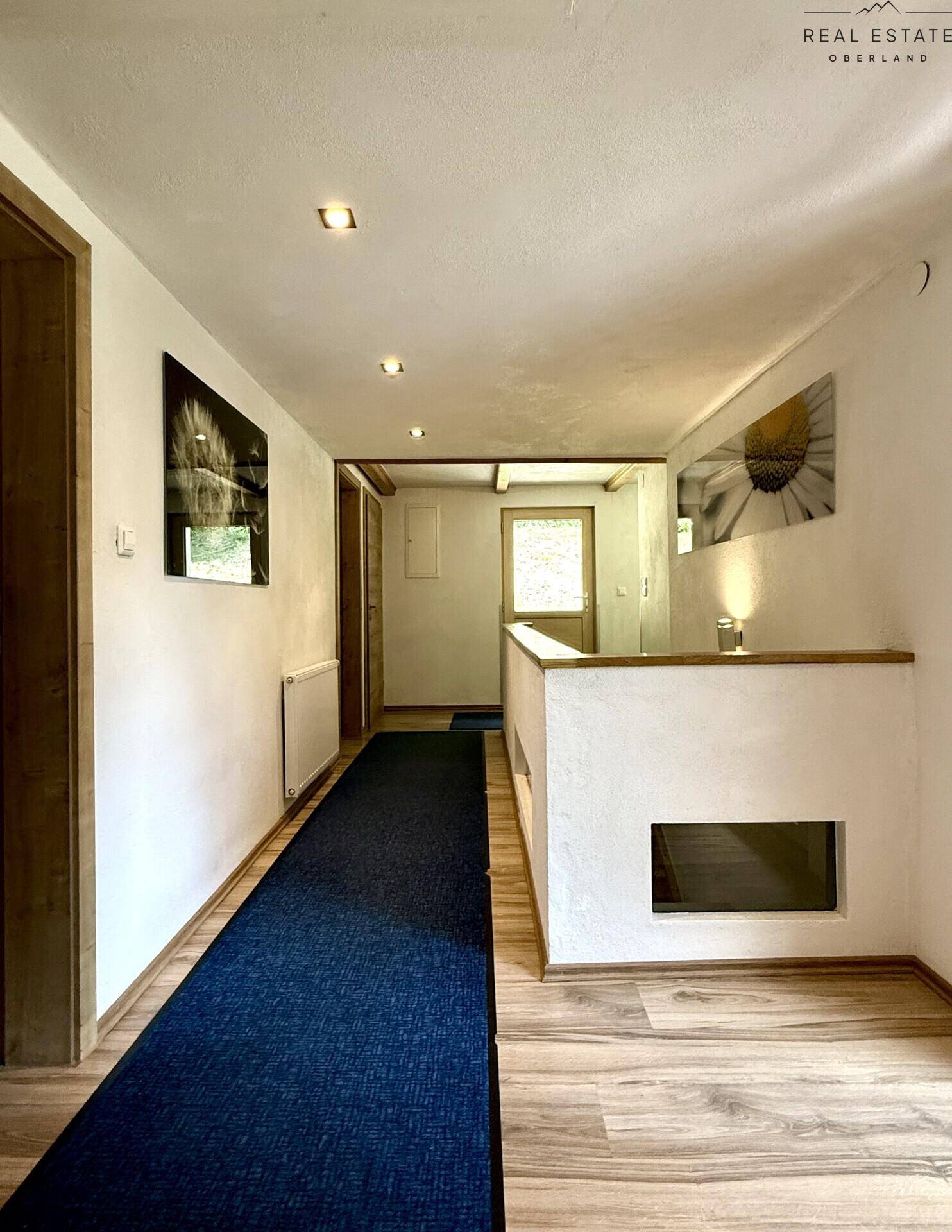 Heller Flur mit Holzfußboden und Teppichläufer, der zu weiteren Räumen führt.