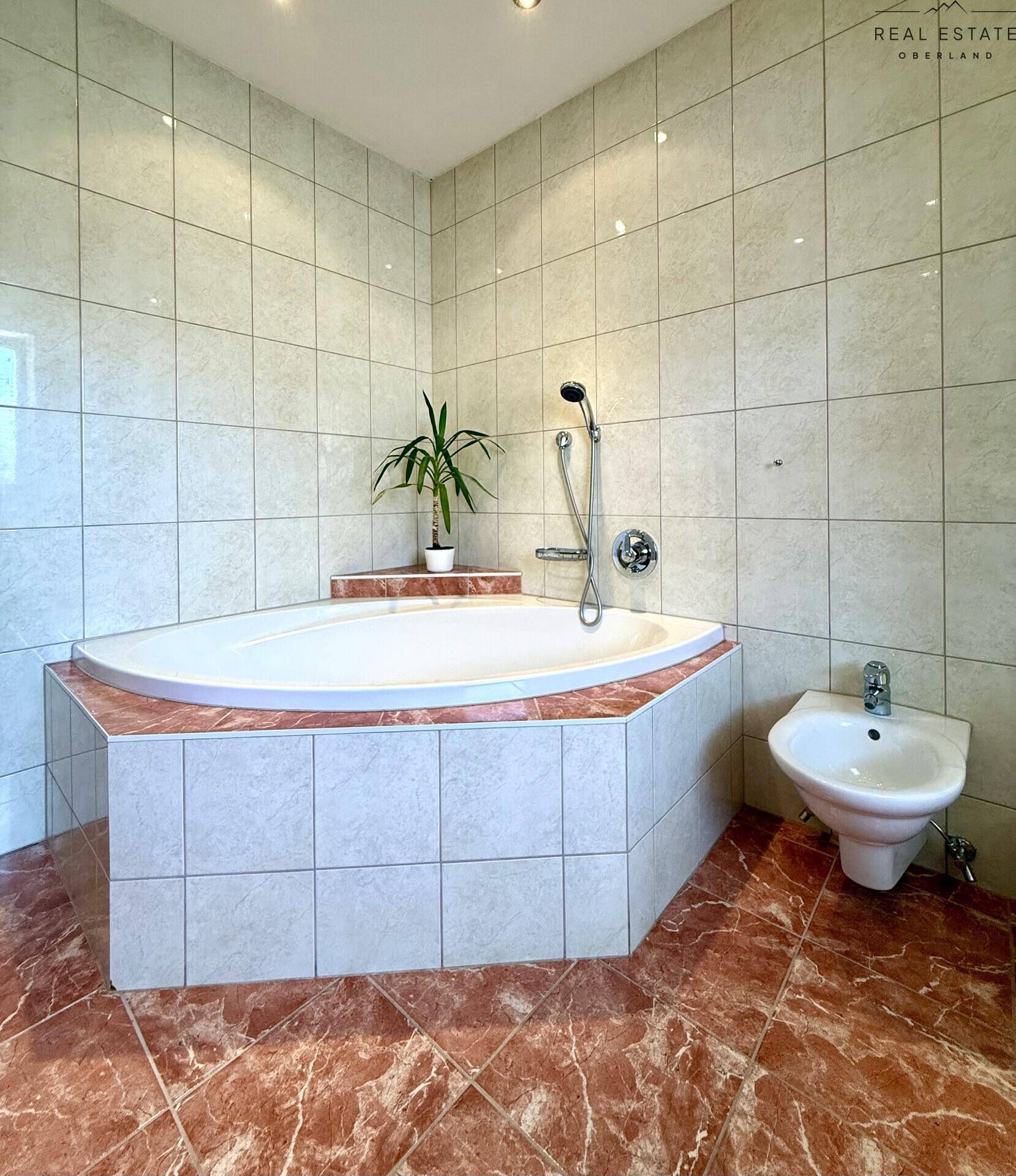 Badezimmer mit Eckbadewanne, Bidet und gefliestem Boden, bietet Komfort und Funktionalität.