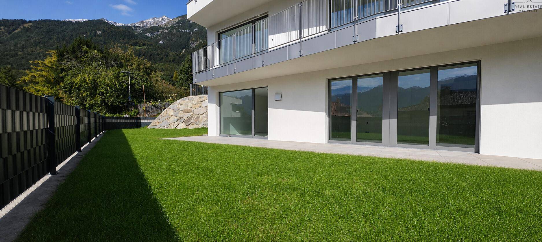 Gepflegter Rasenbereich neben dem modernen Gebäude mit Blick auf die Berge.