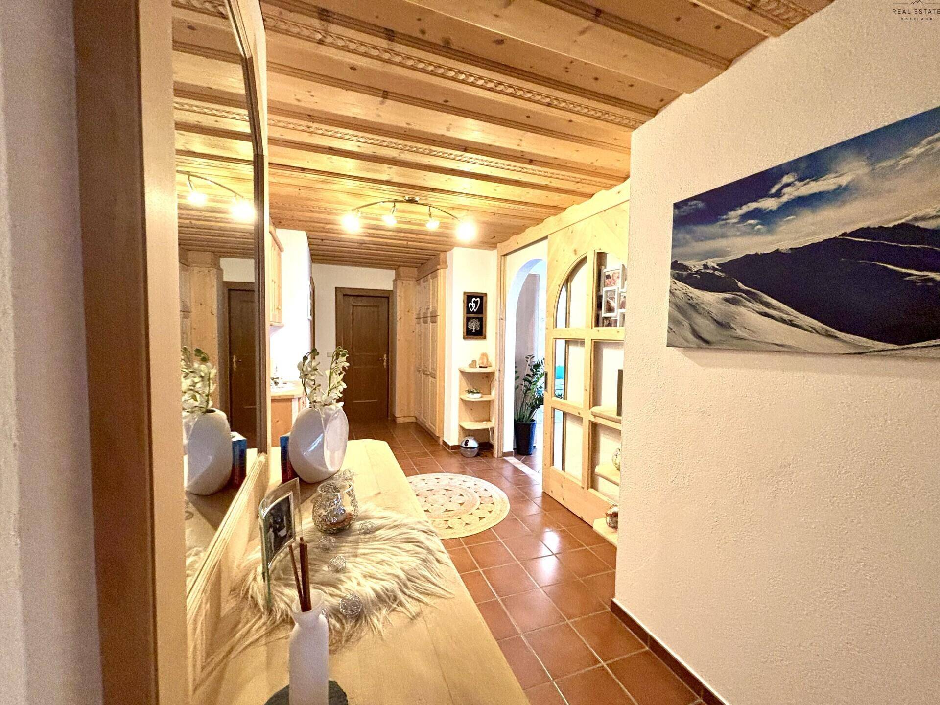 Geräumiger Flur mit Holzvertäfelung an Decke und Wänden, Terrakottafliesen und einem großen Spiegel.
