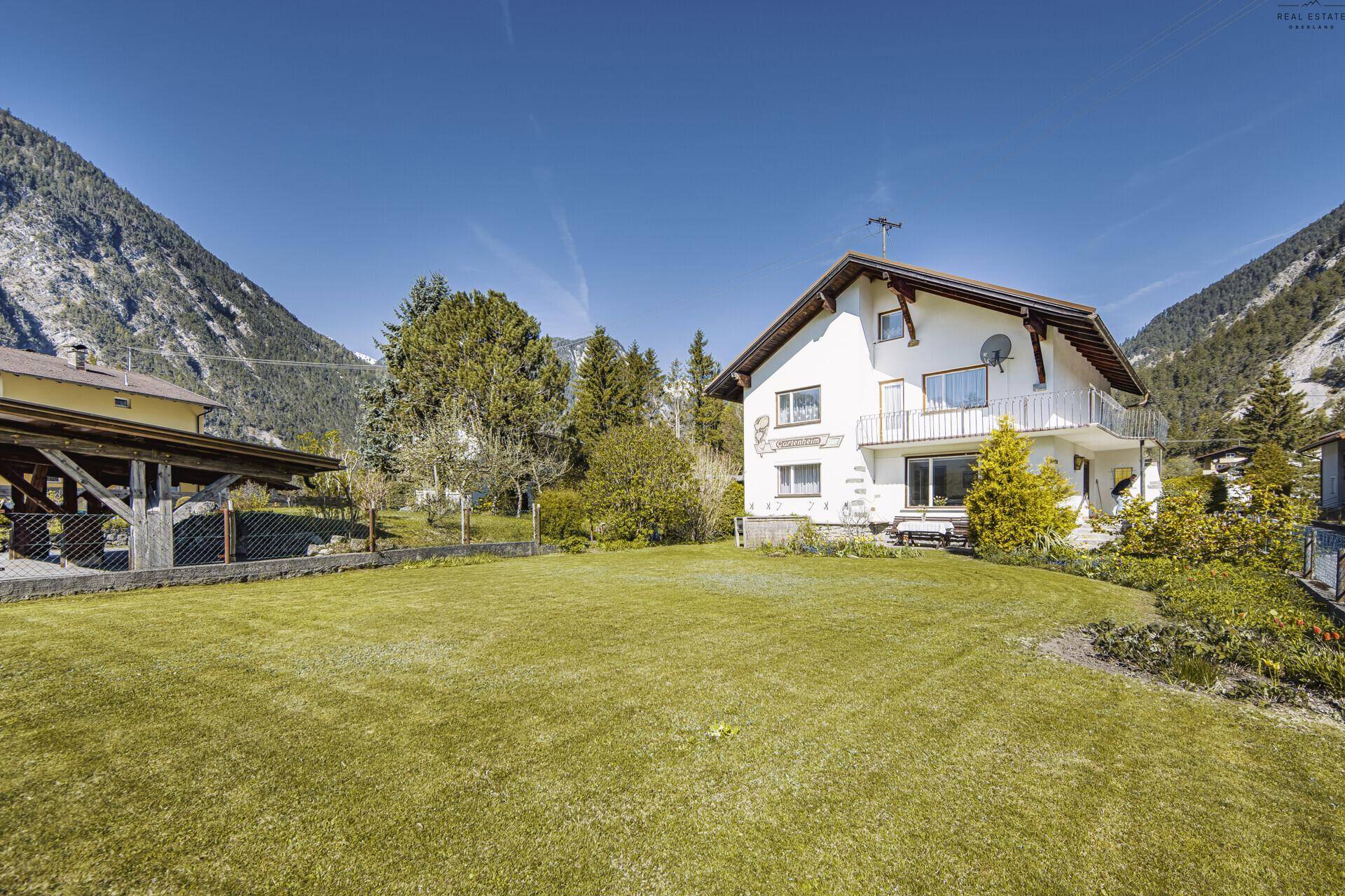 Geräumiger Gartenbereich mit gepflegtem Rasen und Blick auf die umliegenden Berge.