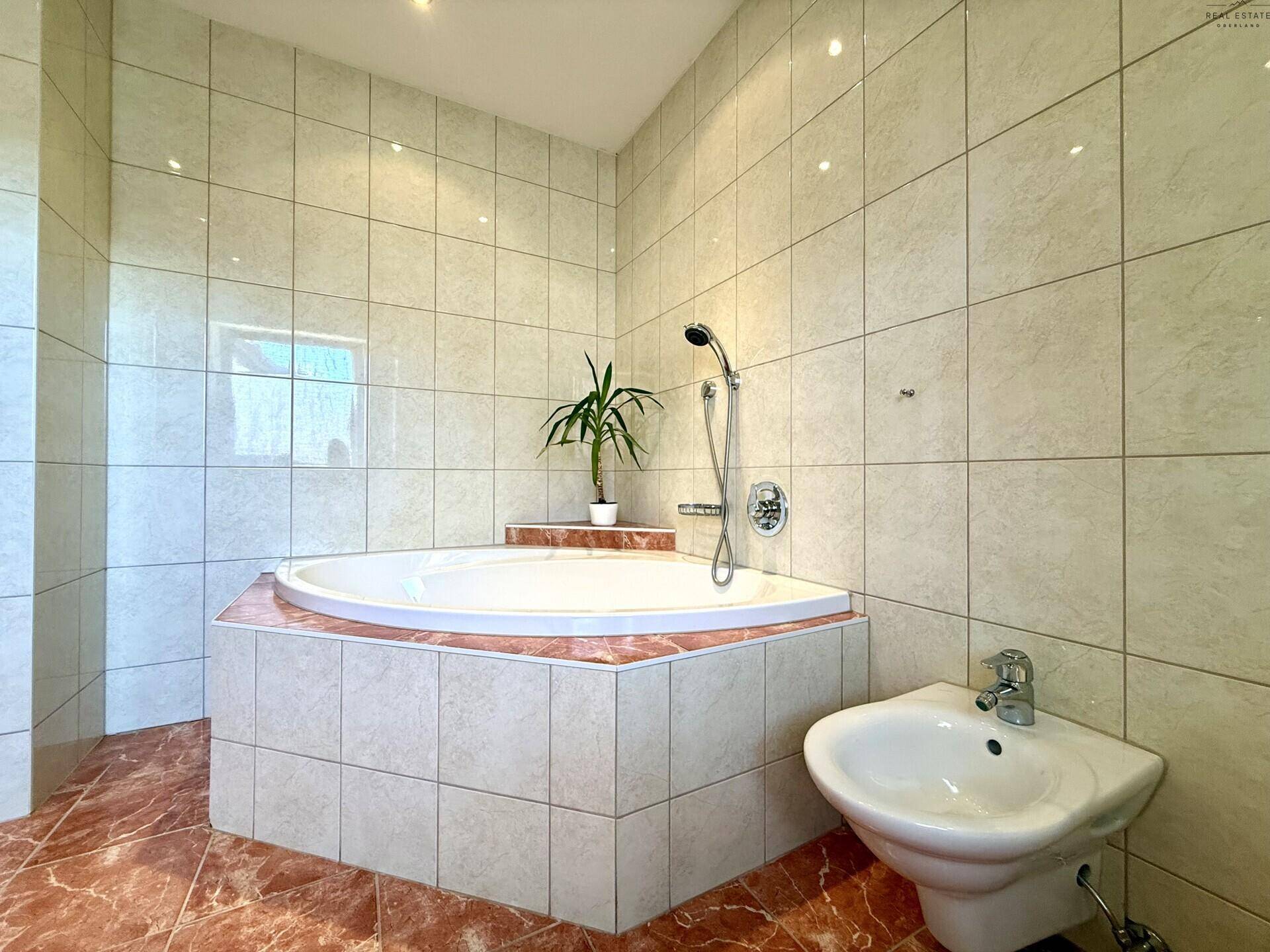 Badezimmer mit Eckbadewanne und separatem Waschbecken, bietet eine entspannende Atmosphäre.
