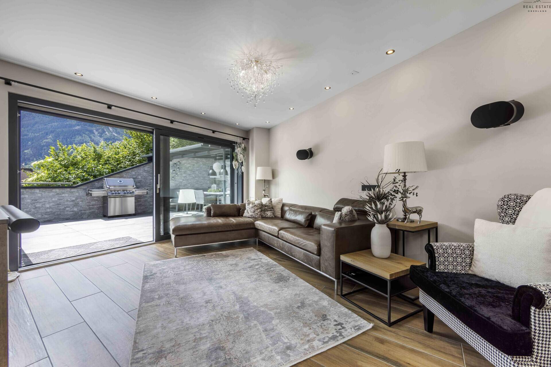 Komfortabler Wohnbereich mit großem Sofa und Zugang zu einer Außenterrasse mit Grill.