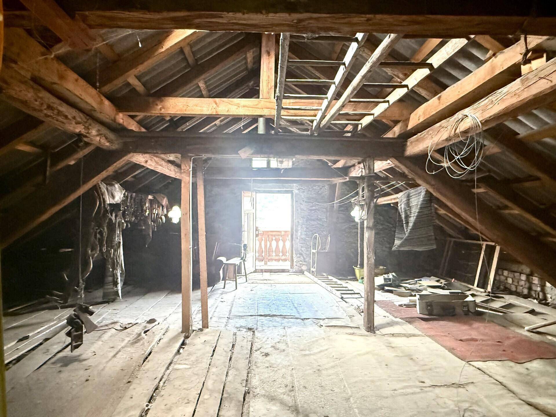 Heller Dachboden mit Holzbalken und Zugang zu einem kleinen Balkon, ideal für Ausbau.