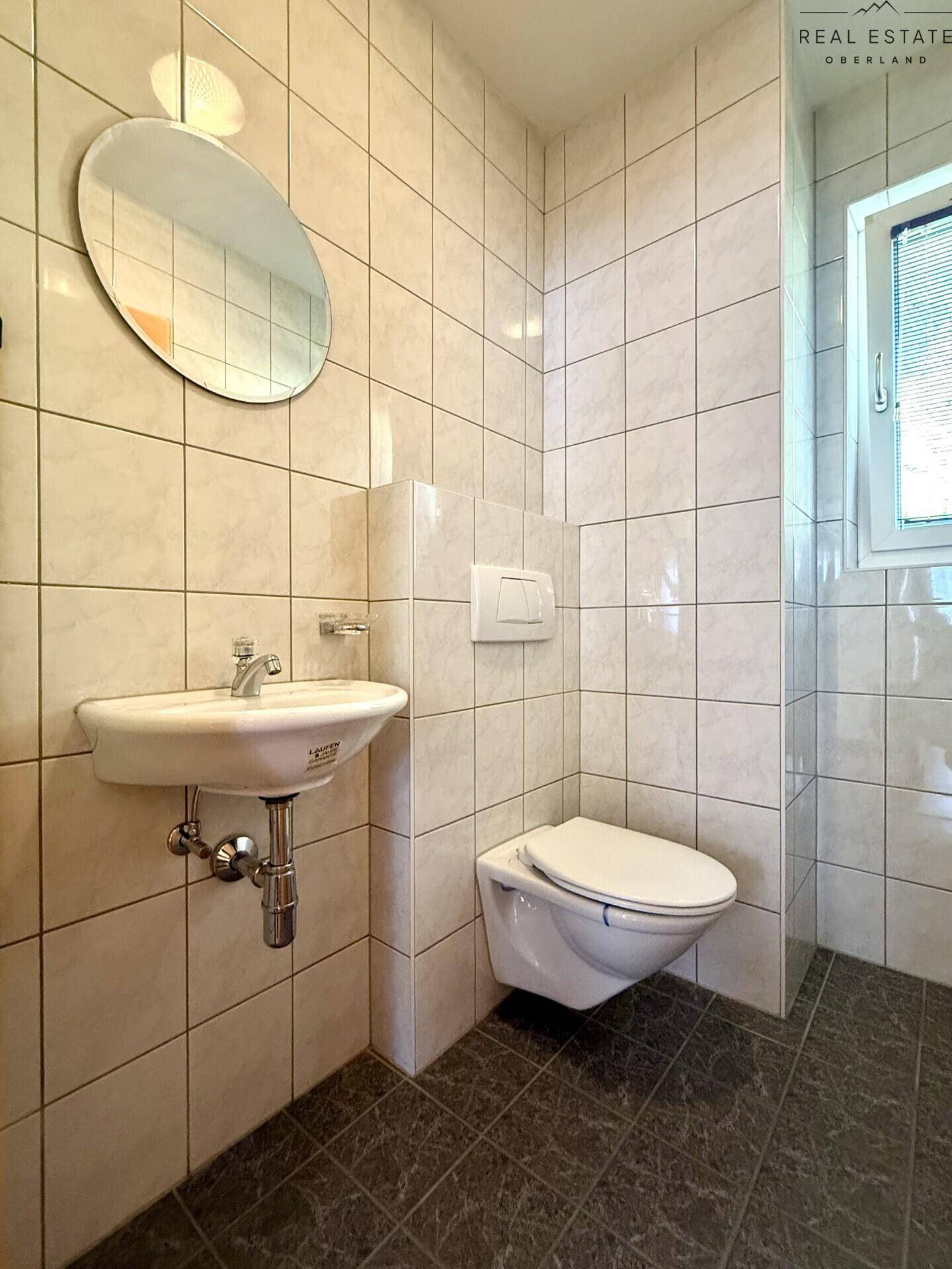 Modernes Gäste-WC mit wandhängendem WC, Waschbecken und Fenster.