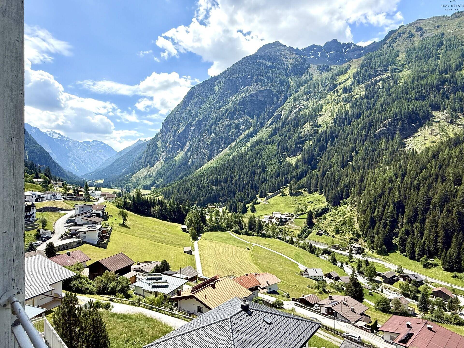 Weitläufiger Ausblick von einem Balkon auf die beeindruckende Berglandschaft und das Tal.