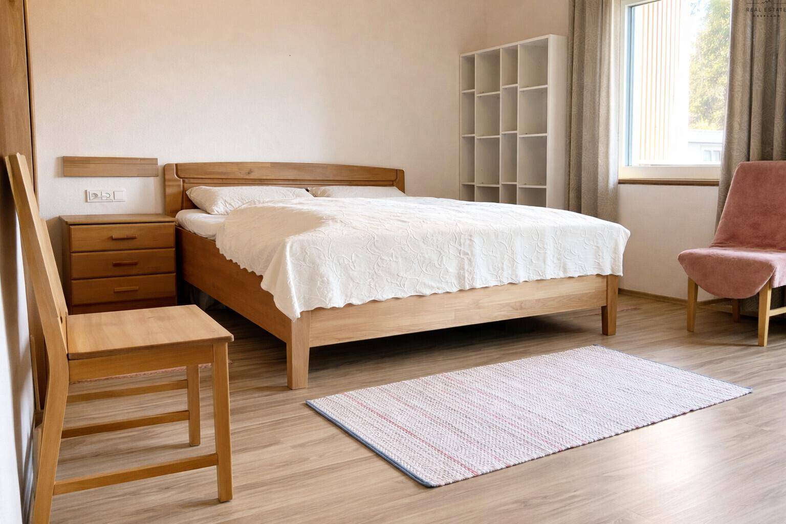Gemütliches Schlafzimmer mit hellem Holzbett, Nachttischen und Laminatboden, gut beleuchtet.