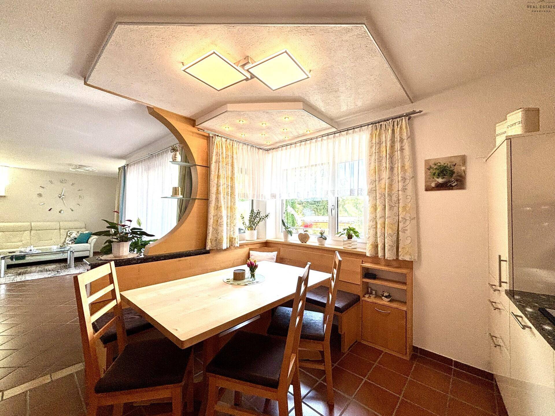 Offener Wohn- und Essbereich mit heller Eckbank, Fliesenboden und Blick in das angrenzende Wohnzimmer.