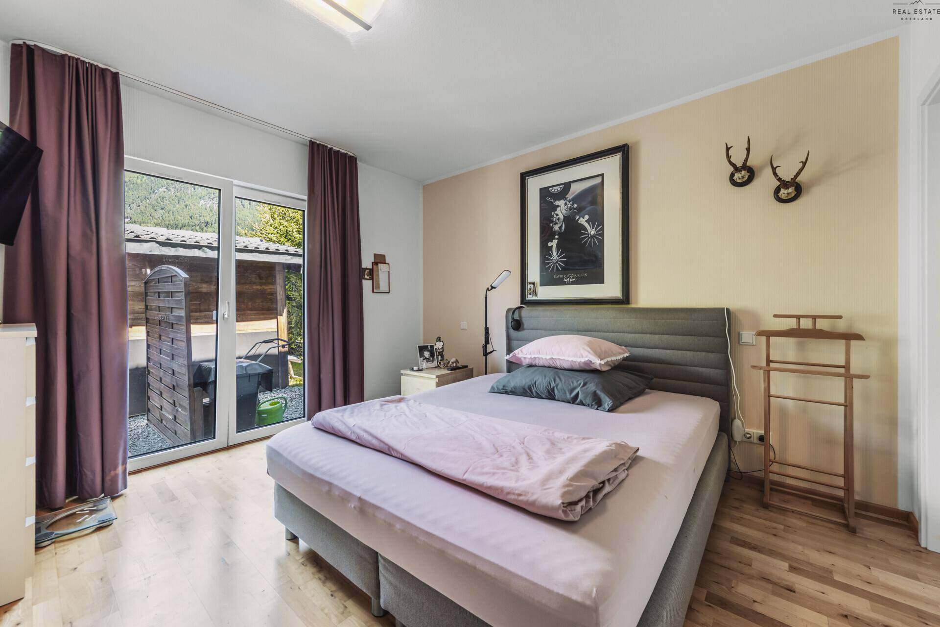 Schlafzimmer mit Doppelbett, Holzboden und direktem Zugang zu einem Außenbereich.