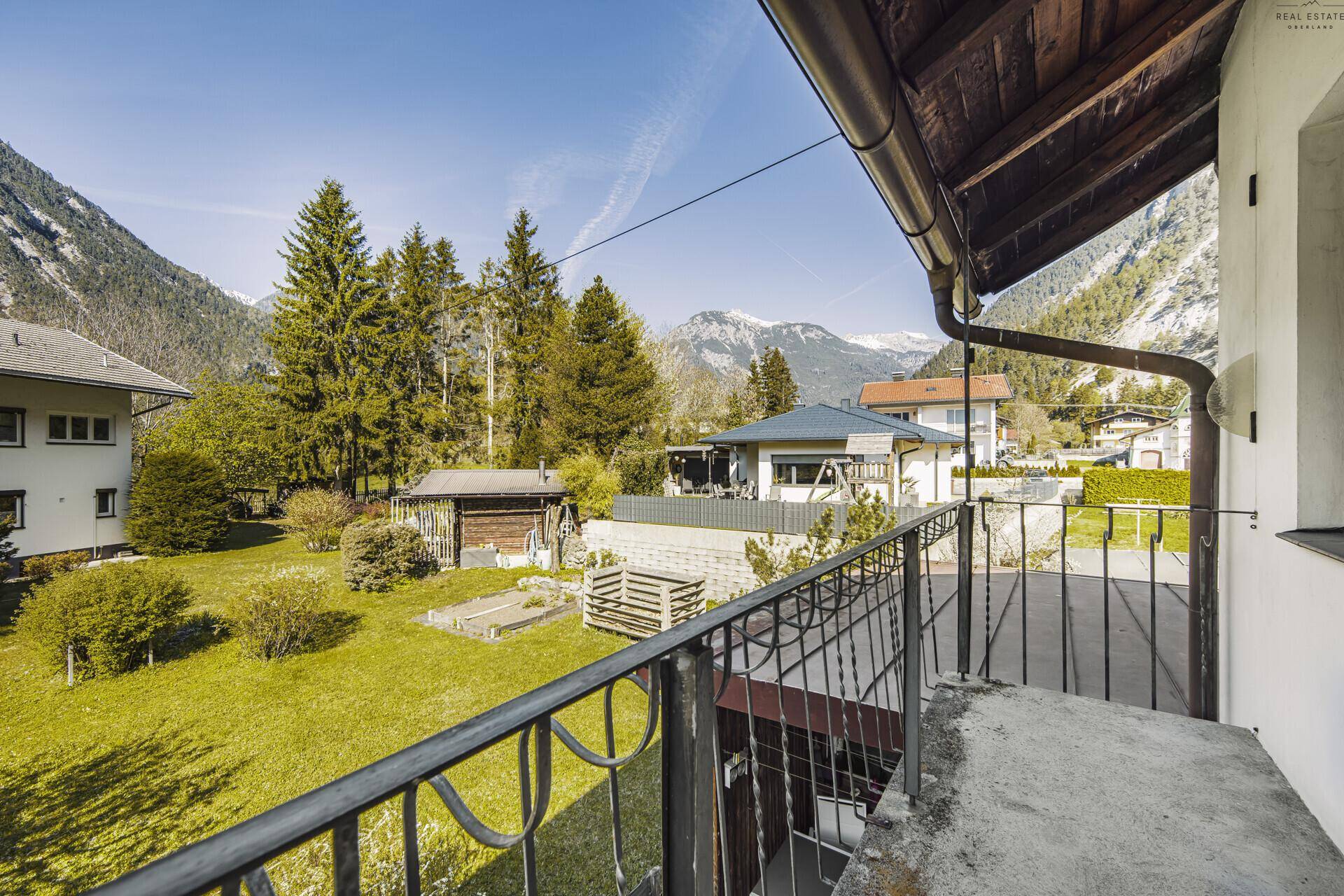Kleiner Balkon mit Blick auf den Garten und die dahinterliegenden Berge.