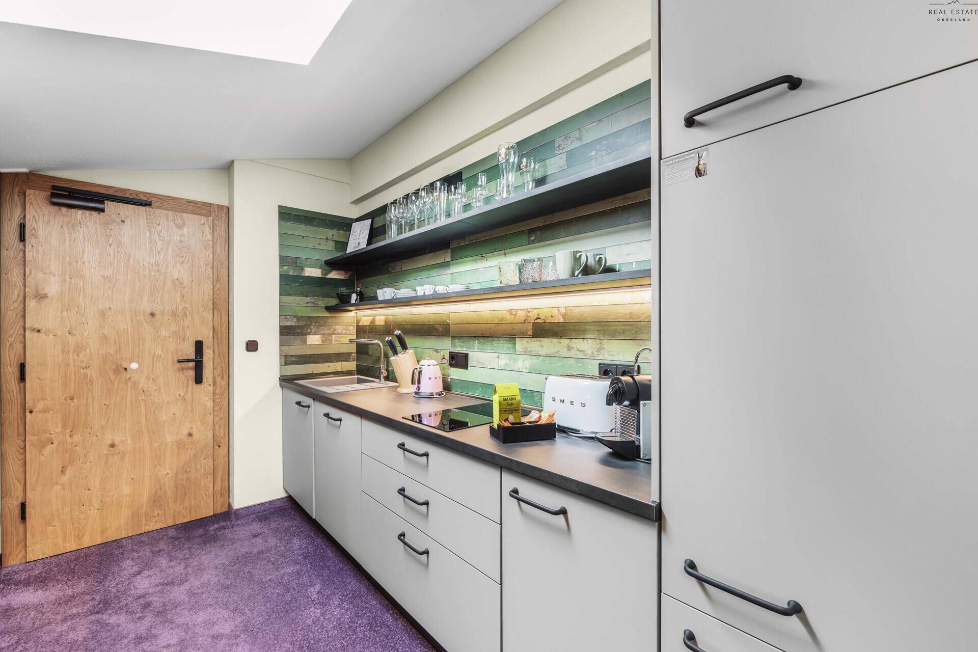 Moderne Küchenzeile mit grauen Schränken, Holzdetails und lila Teppichboden.