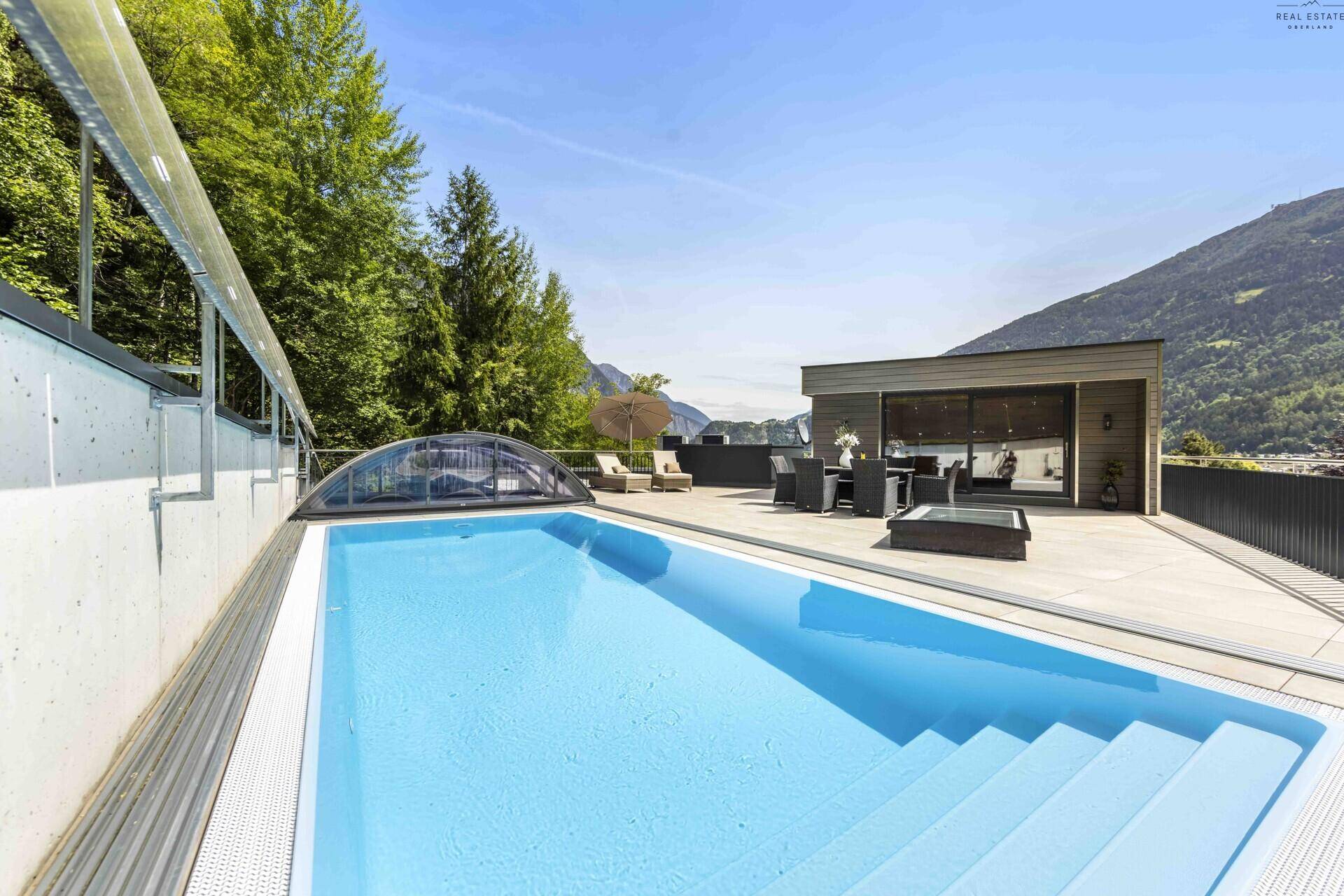 Weitläufige Terrasse mit Schwimmbecken und Entspannungsbereich, bietet einen atemberaubenden Blick auf die Berge.