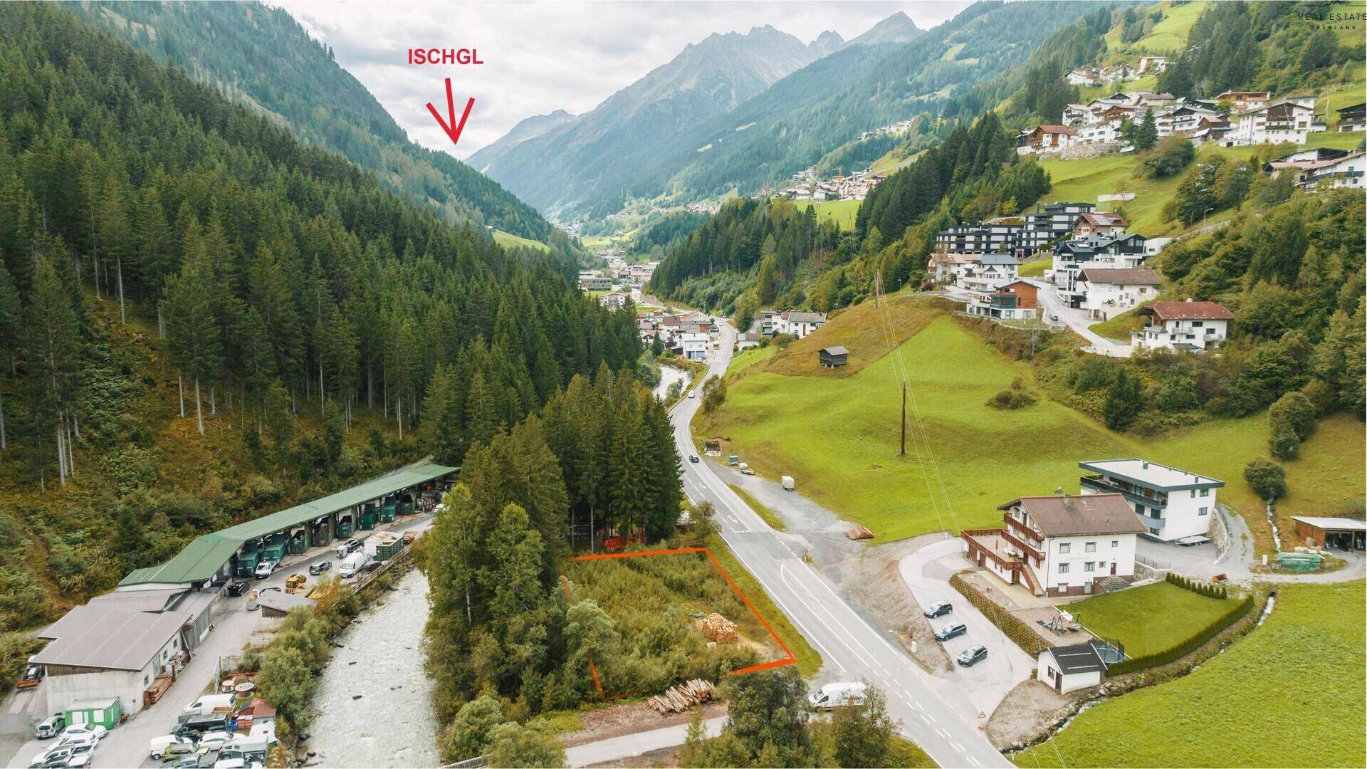 Luftaufnahme eines Tals mit markiertem Grundstück, umgeben von Bergen und Wäldern, mit Hinweis auf Ischgl.