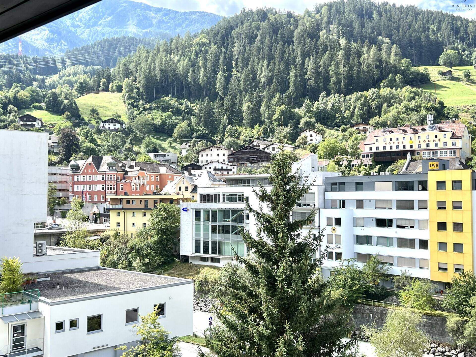 Panoramablick auf eine Berglandschaft mit üppigen Wäldern und einer Siedlung im Tal.