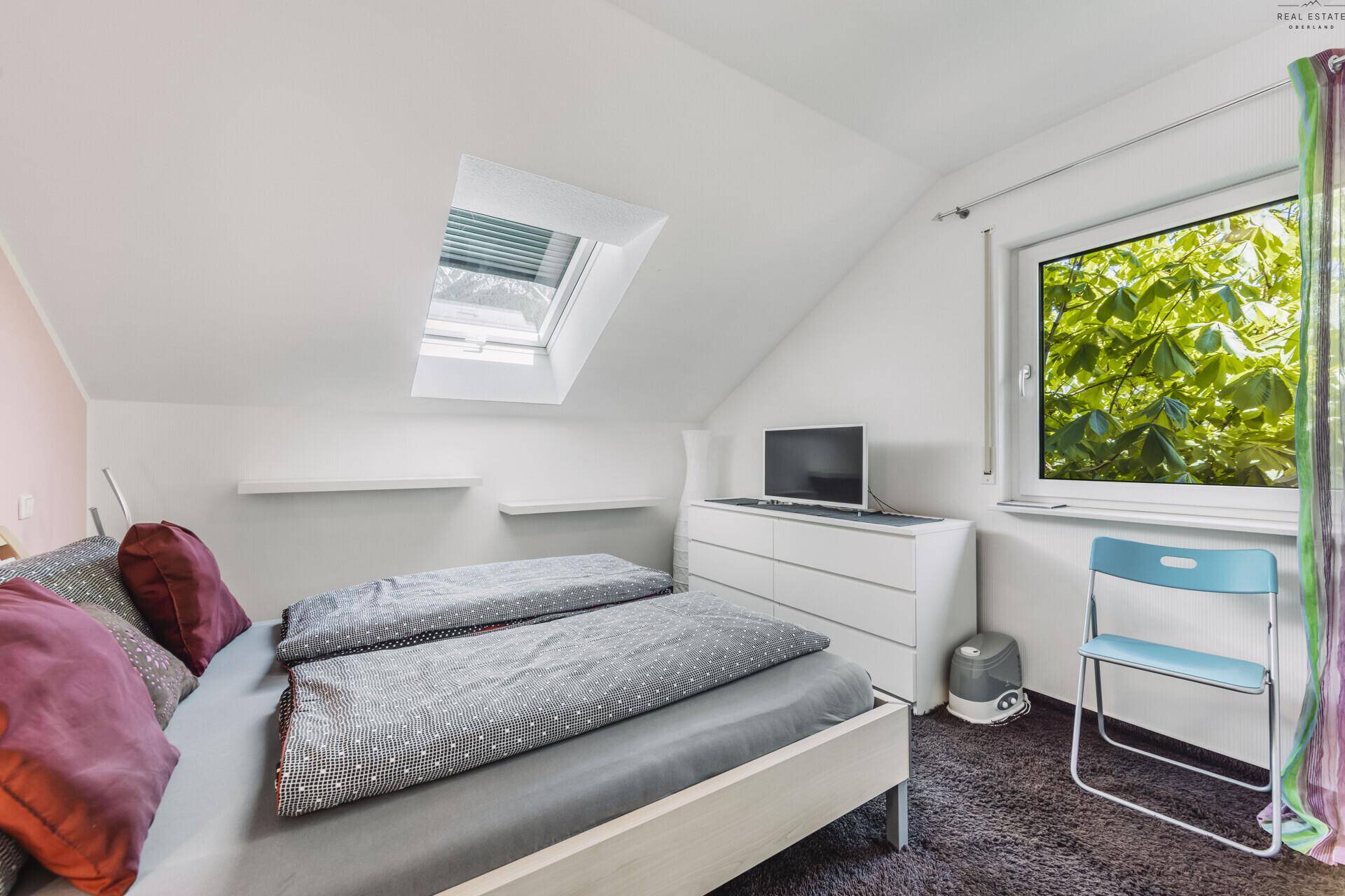 Helles Schlafzimmer im Dachgeschoss mit Dachfenster und Blick ins Grüne.