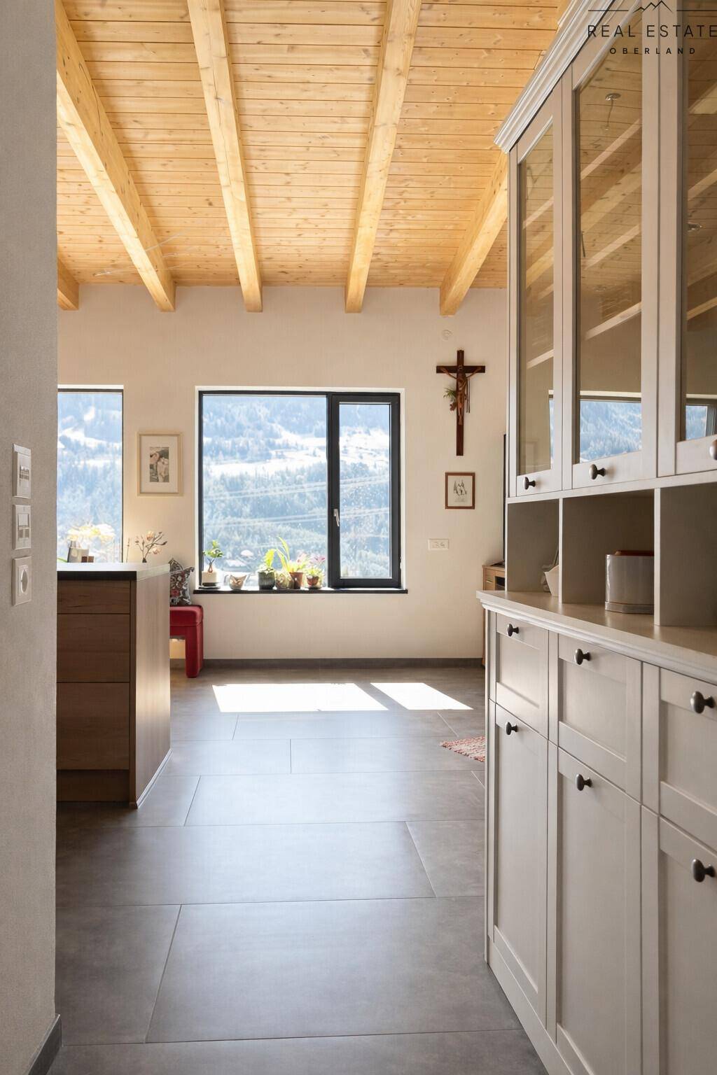 Heller Flur mit Holzbalkendecke, Blick auf die Berge durch ein Fenster und weißem Schrank.