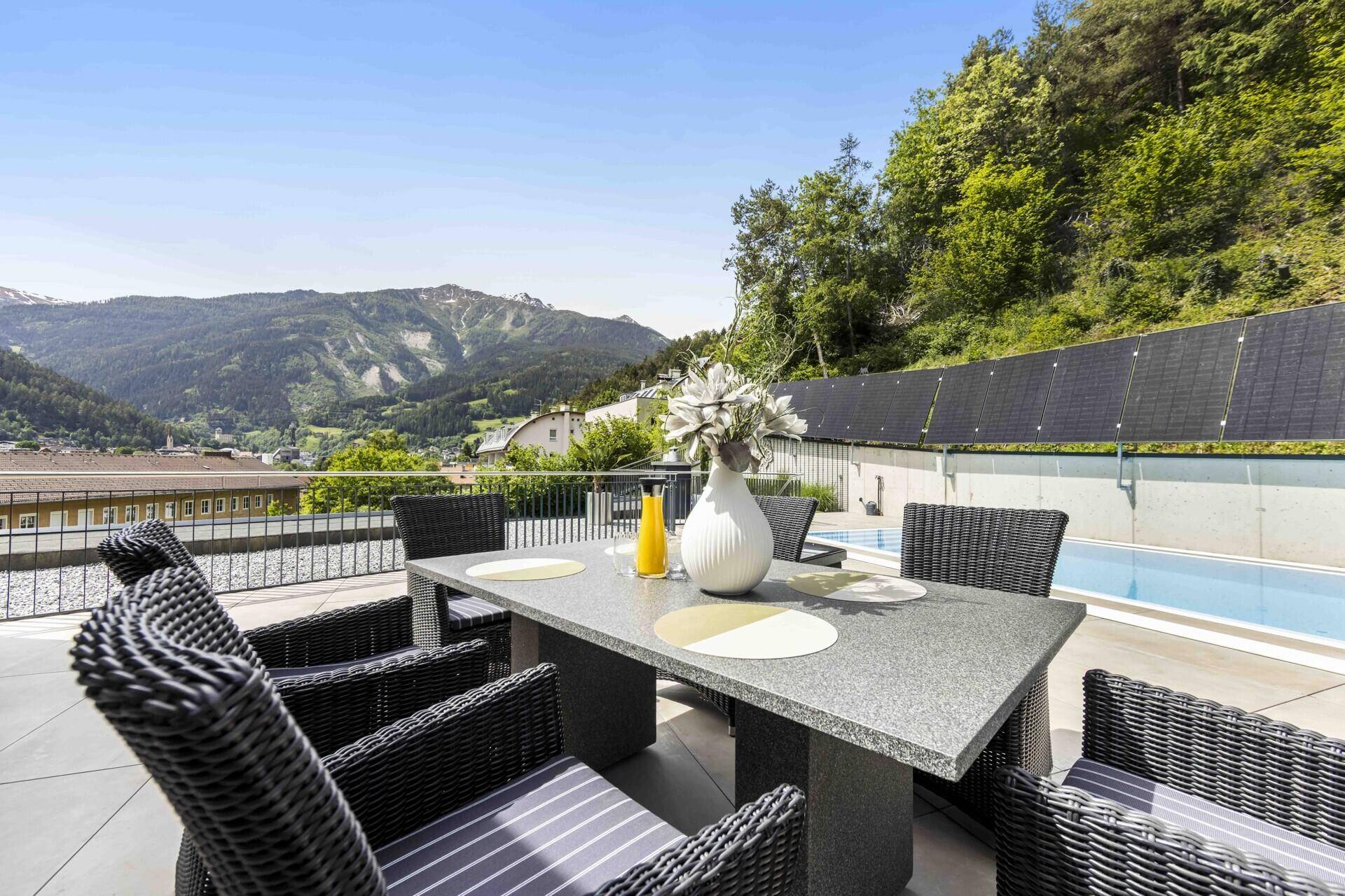 Gemütlicher Essbereich auf der Terrasse mit Blick auf die Berge und den Poolbereich im Hintergrund.