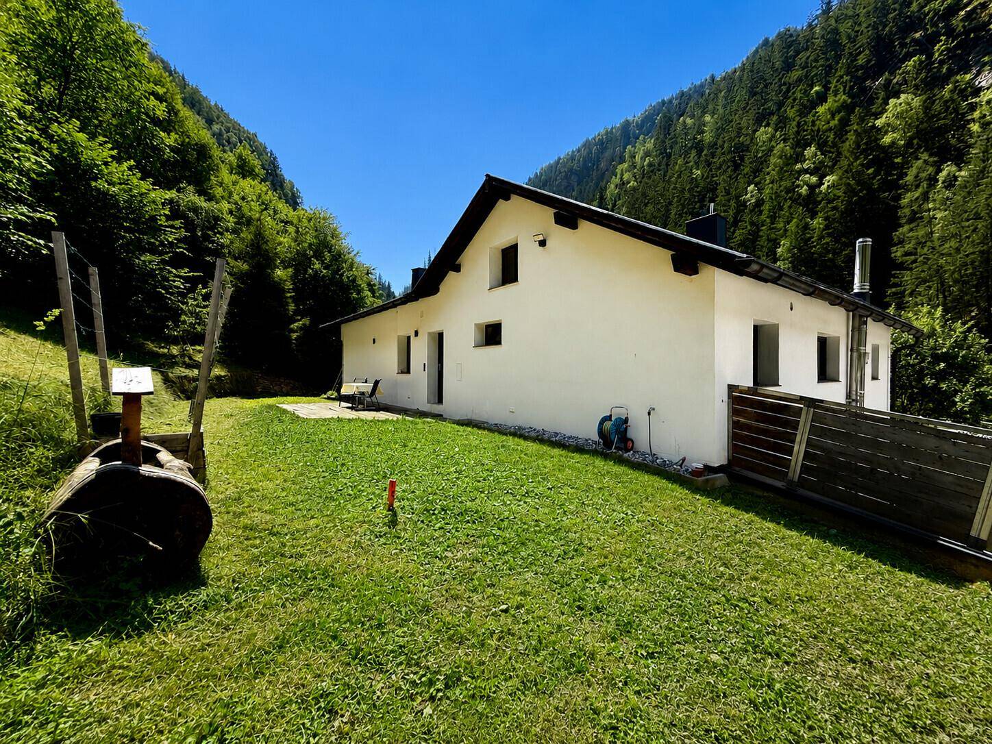 Großer Rasenbereich neben dem Haus mit Blick auf die umliegenden bewaldeten Berge.