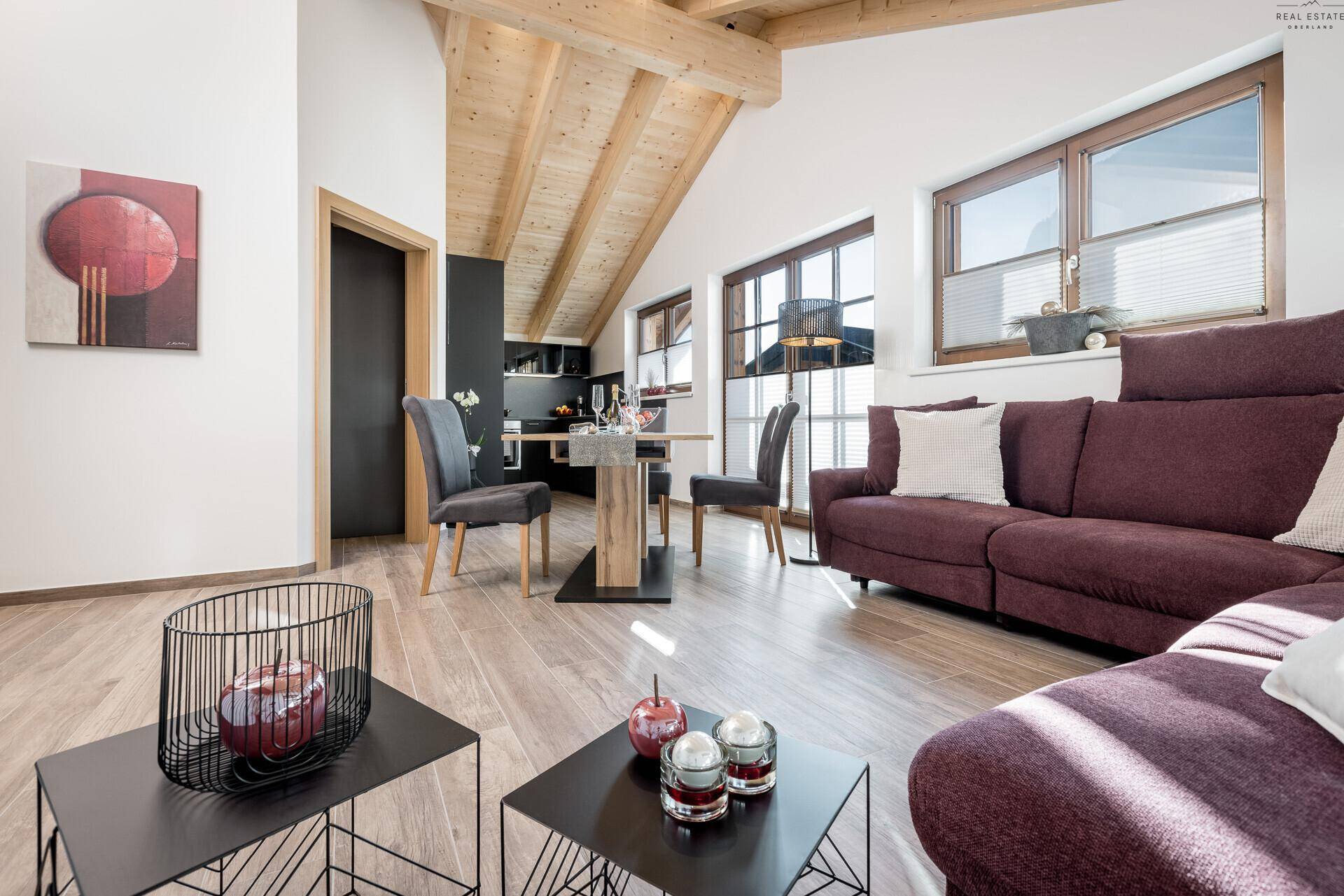 Helles Wohn- und Esszimmer mit Holzbalkendecke, Parkettboden und moderner Einrichtung.