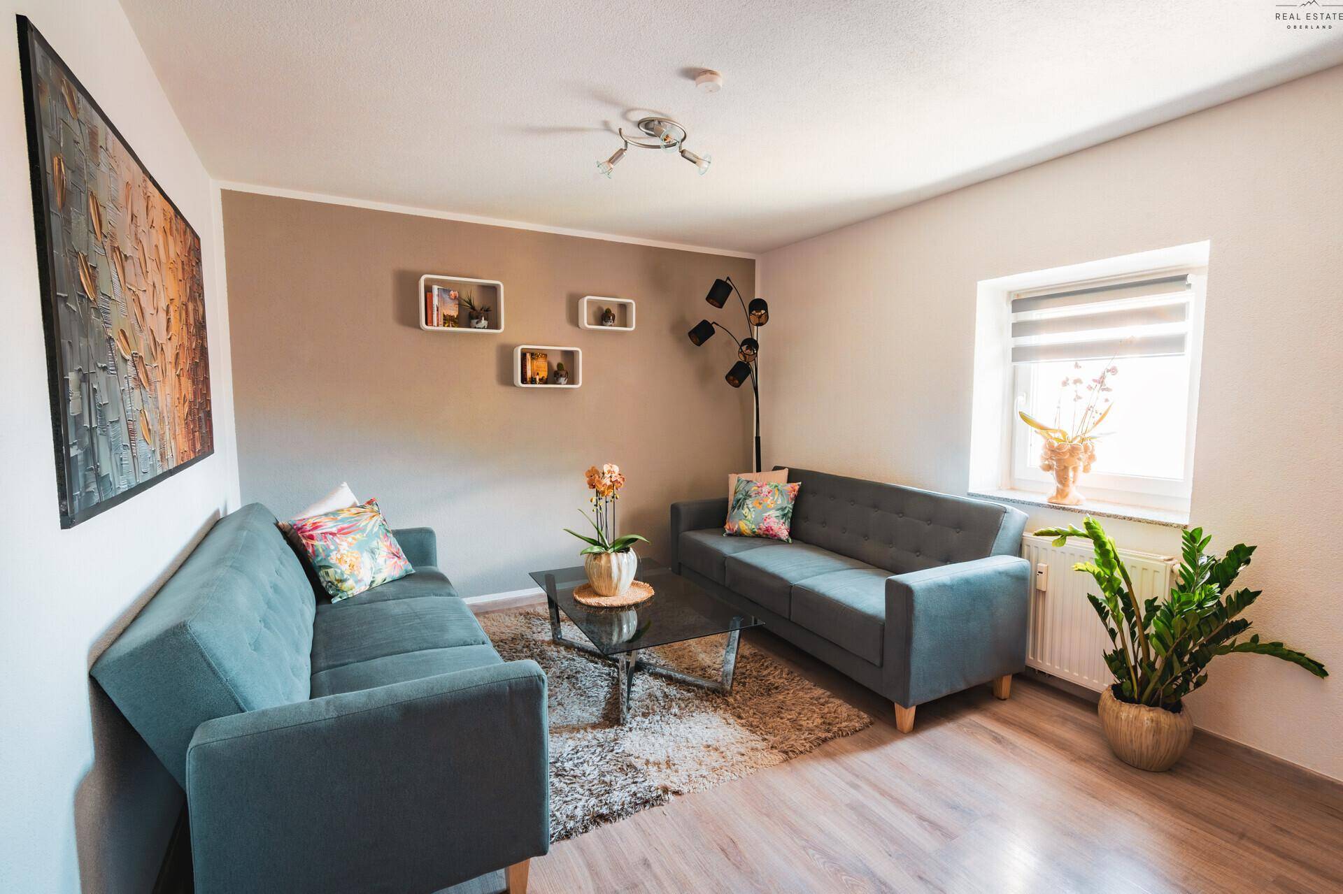 Gemütliches Wohnzimmer mit zwei grauen Sofas, Glas-Couchtisch und modernem Dekor.