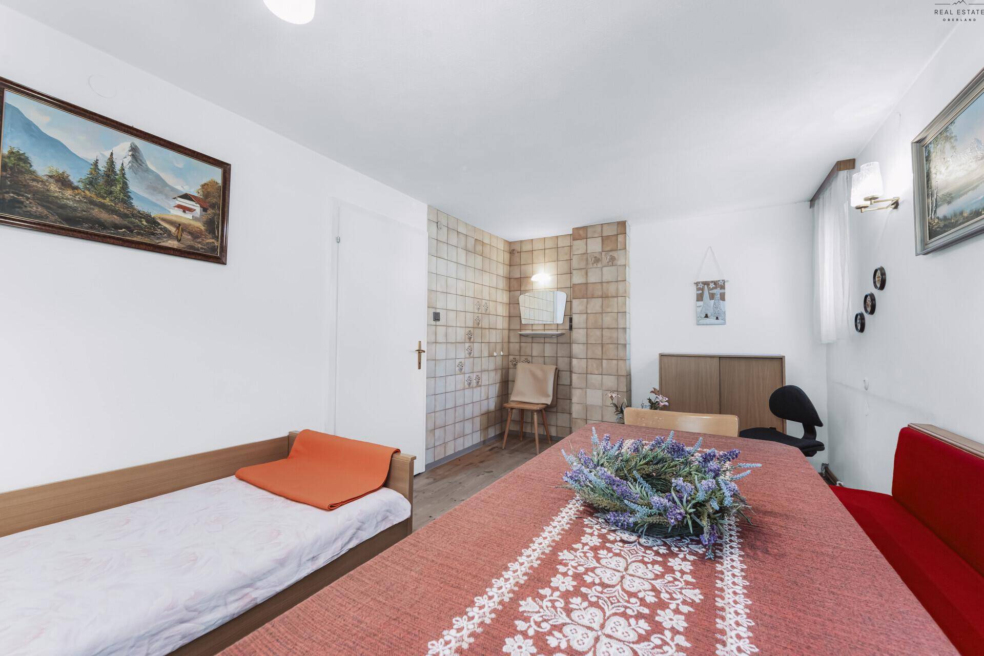 Gemütlicher Essbereich mit Holztisch, Eckbank und einem Einzelbett, traditionell eingerichtet.