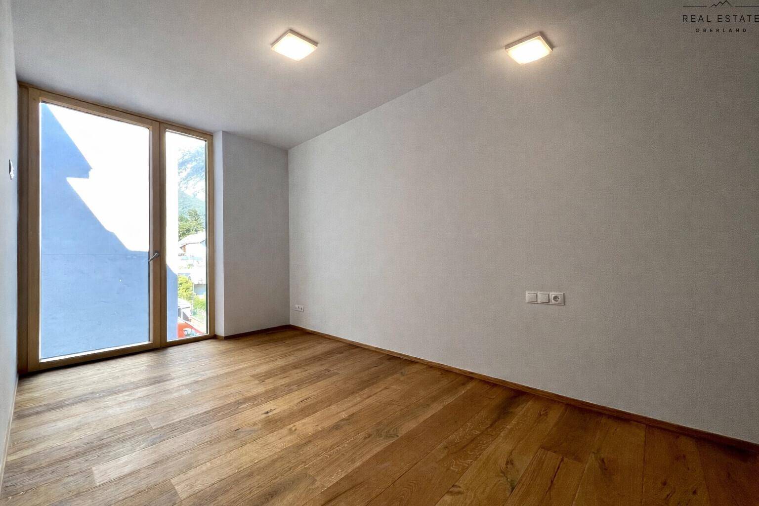 Helles Schlafzimmer mit Holzfußboden und Zugang zu einem Balkon oder einer Terrasse.