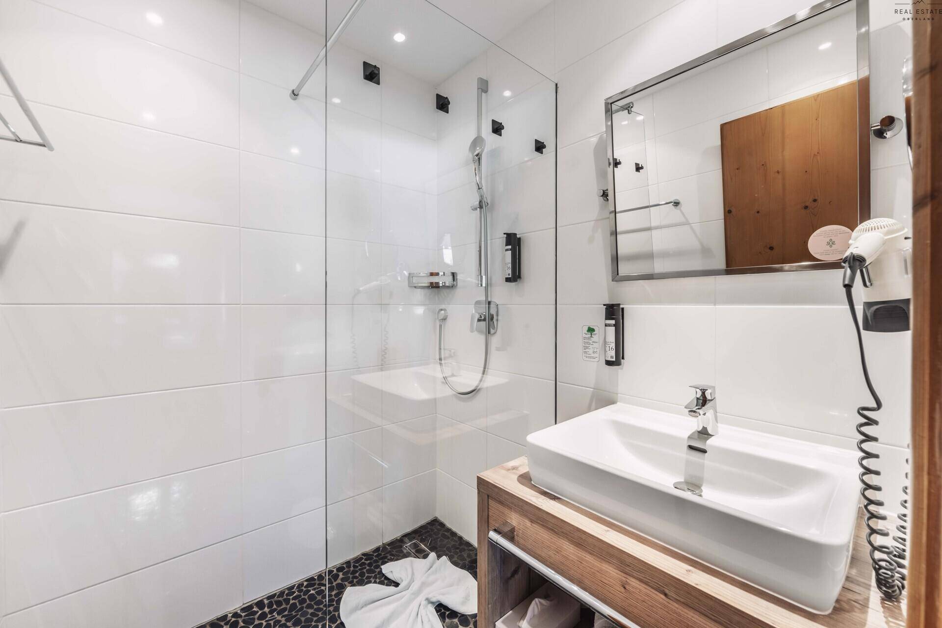Modernes Badezimmer mit weiß gefliesten Wänden, begehbarer Dusche und Einzelwaschbecken.