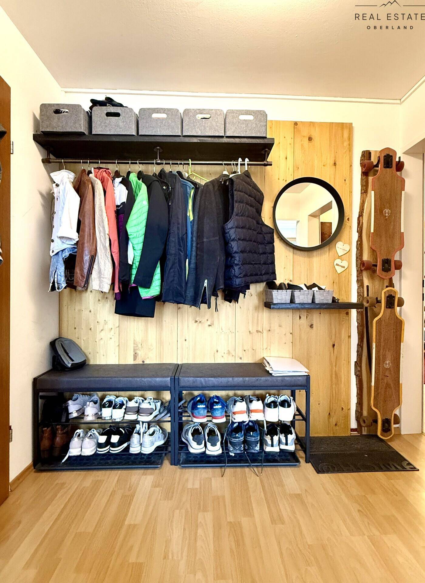 Heller Eingangsbereich mit Holzverkleidung, Garderobe und Schuhregal.
