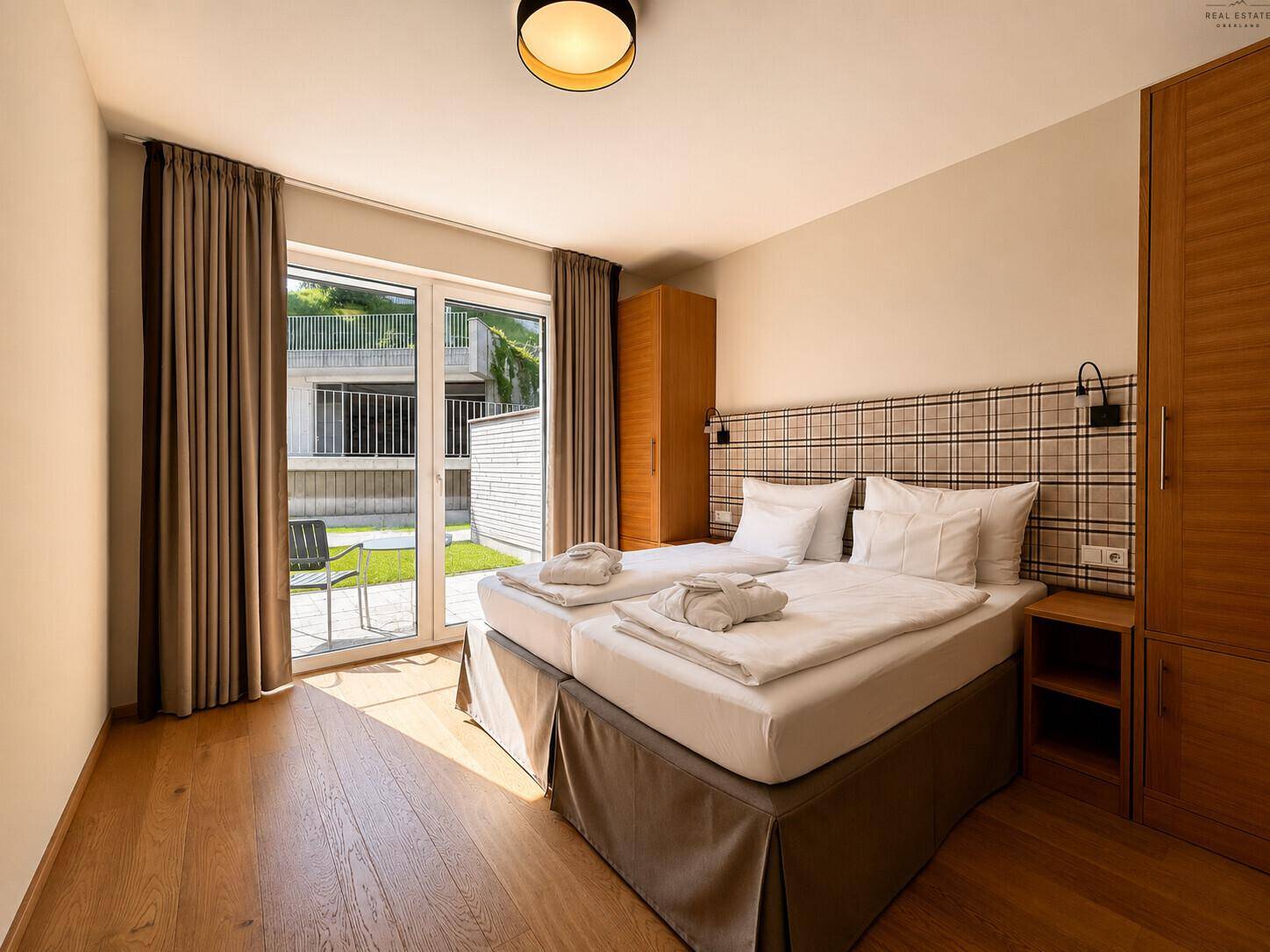 Helles Schlafzimmer mit Doppelbett, Holzfußboden und direktem Zugang zur Terrasse.
