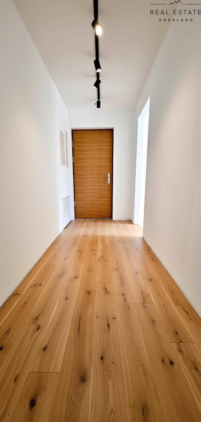 Heller Flur mit Holzboden und einer modernen Holztür.
