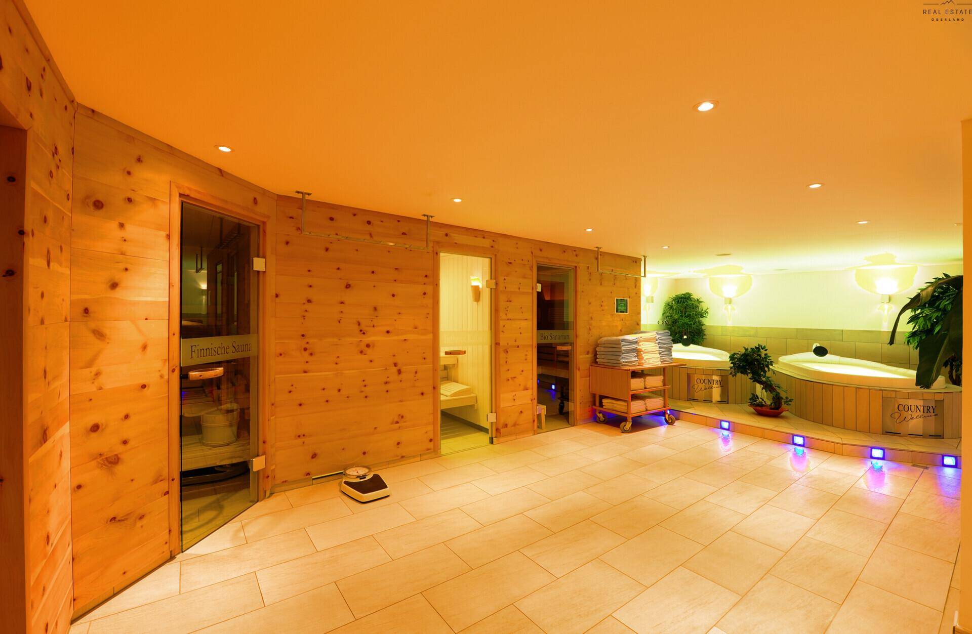 Entspannender Wellnessbereich mit Holzwänden, gefliestem Boden und zwei Whirlpools für die Gäste.