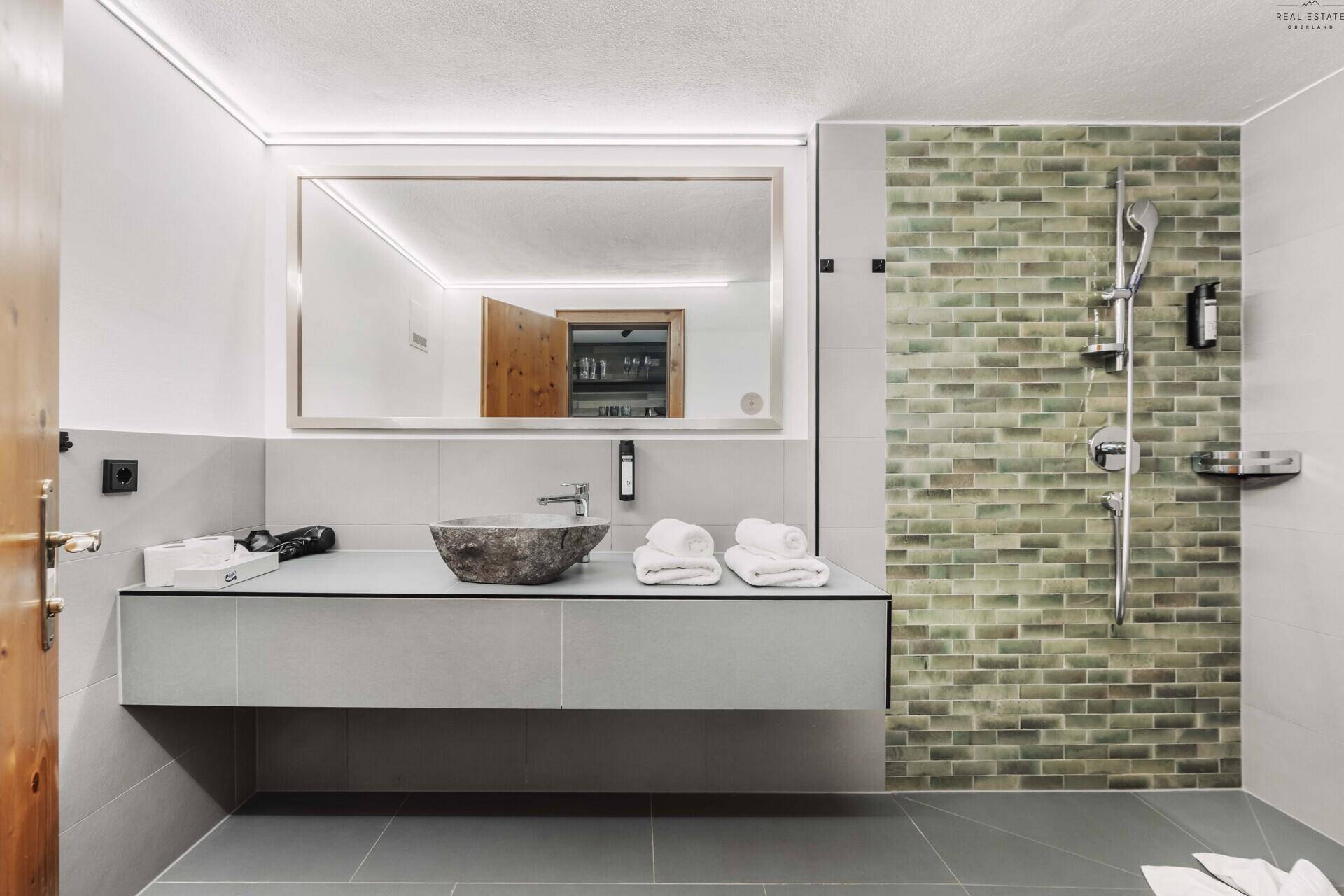 Modernes Badezimmer mit begehbarer Dusche, Steinwaschbecken und stilvollen Fliesen.