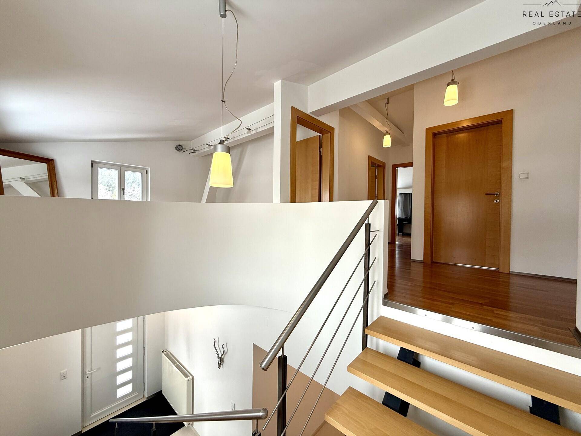 Treppenhaus mit Holzstufen und modernem Metallgeländer, das die verschiedenen Ebenen verbindet.