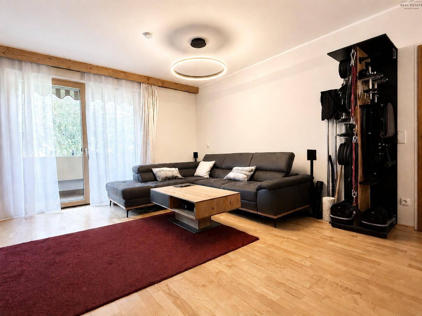 Geräumiges Wohnzimmer mit großem Sofa, Holzboden und Balkonzugang.