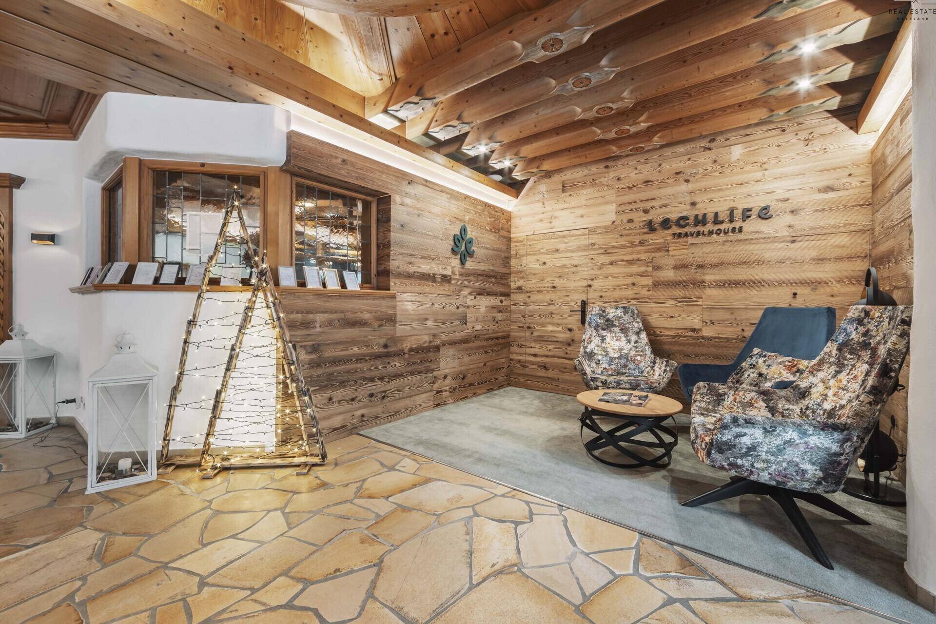 Gemütlicher Empfangsbereich im alpinen Stil mit Holzvertäfelung und Steinboden.