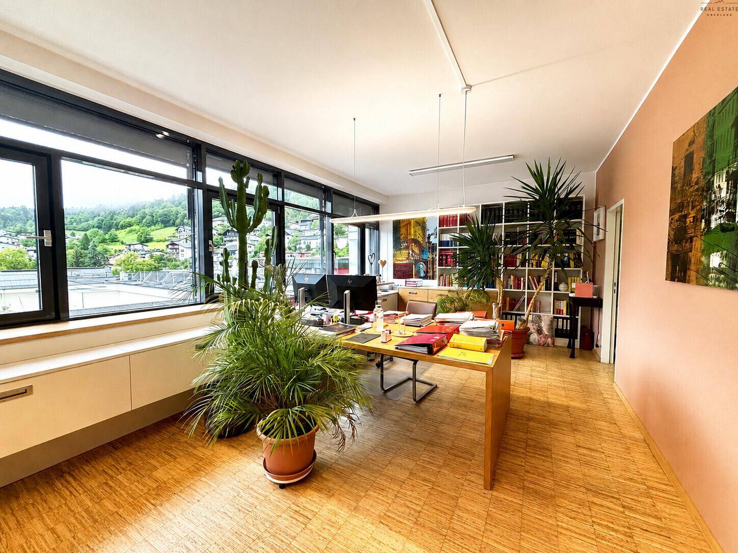 Großes Büro mit mehreren Arbeitsplätzen, vielen Pflanzen und weitem Blick ins Grüne.