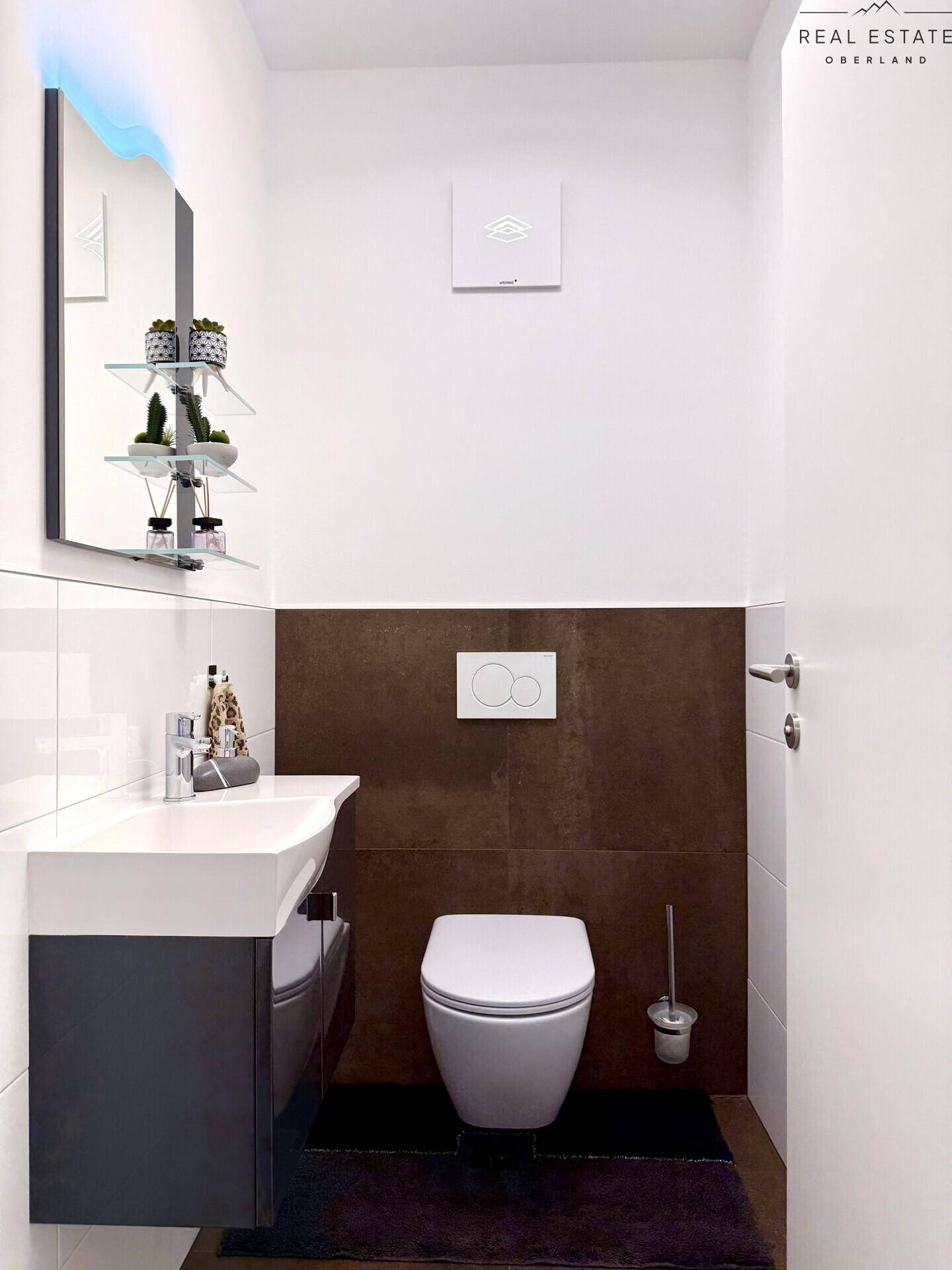 Modernes Gäste-WC mit wandhängender Toilette und stilvollem Waschbecken.