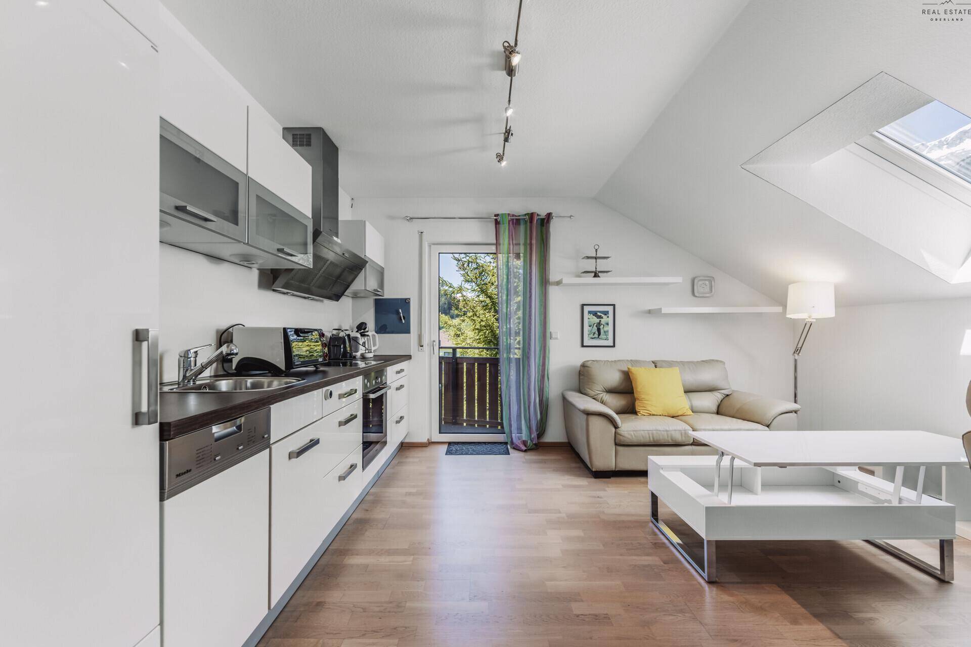 Moderne Küche in der Dachgeschosswohnung mit Einbaugeräten und Balkonzugang.