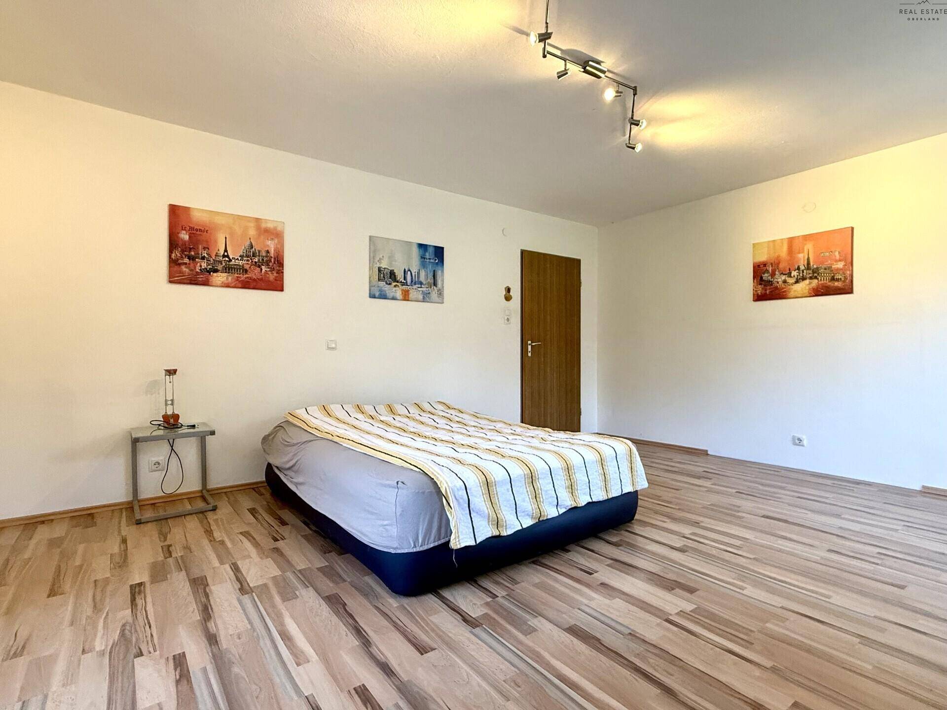 Helles Schlafzimmer mit Laminatboden, einem aufblasbaren Bett und moderner Wanddekoration.