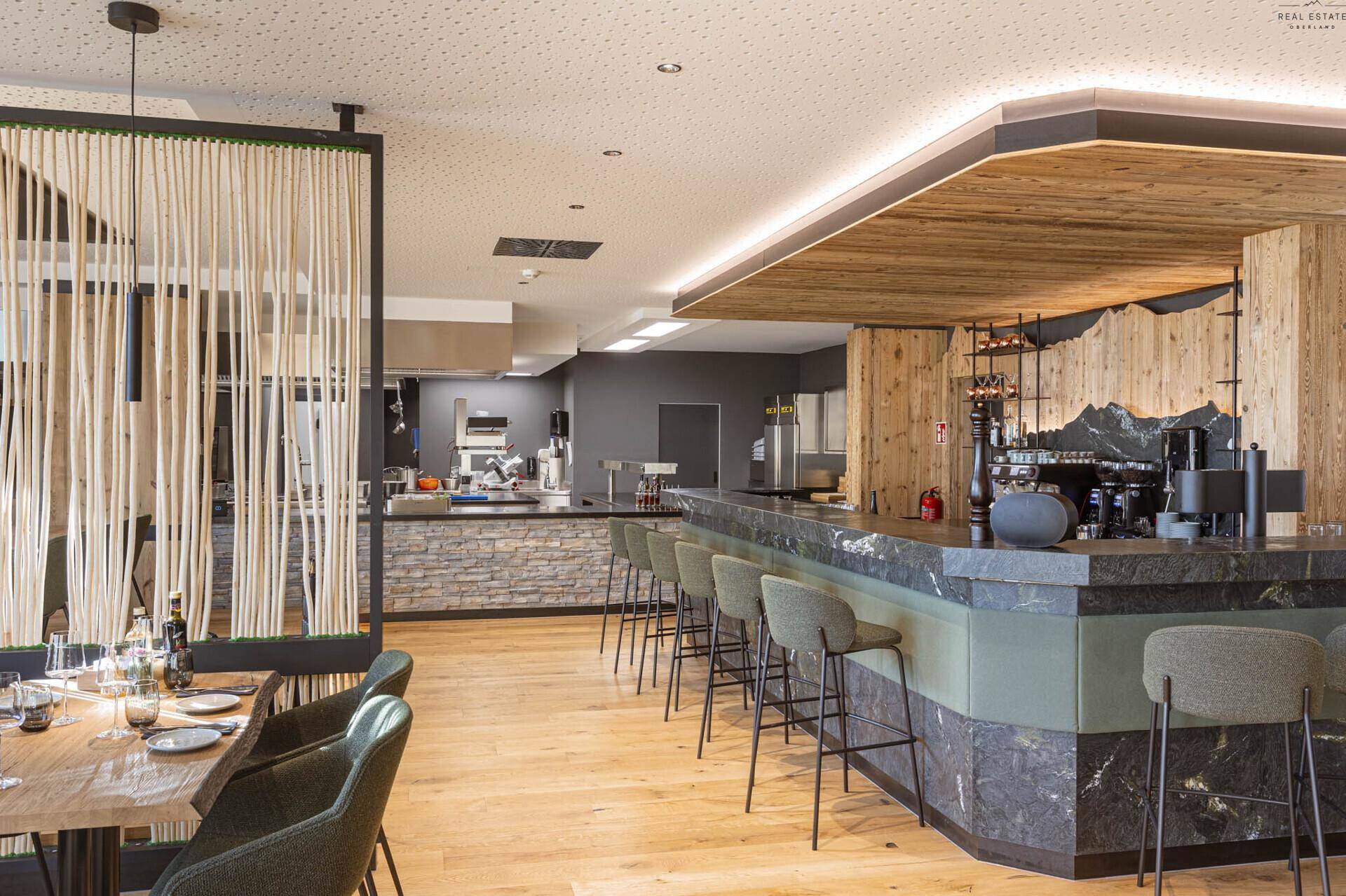 Offener Bereich mit Bar und Essbereich, gekennzeichnet durch Holzelemente und moderne Einrichtung.