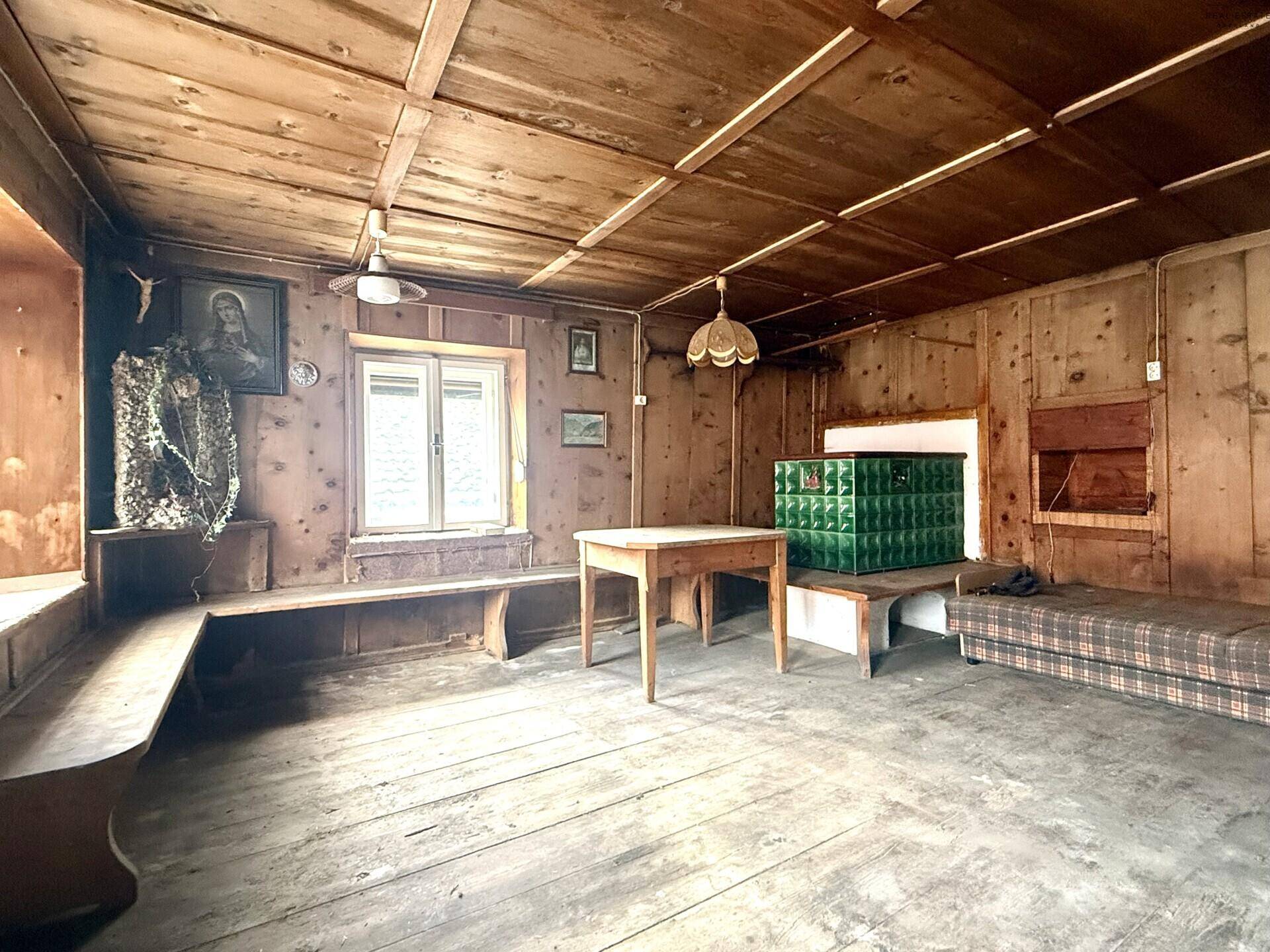 Rustikales Wohnzimmer mit Holztäfelung, Holzboden und traditionellem Kachelofen.
