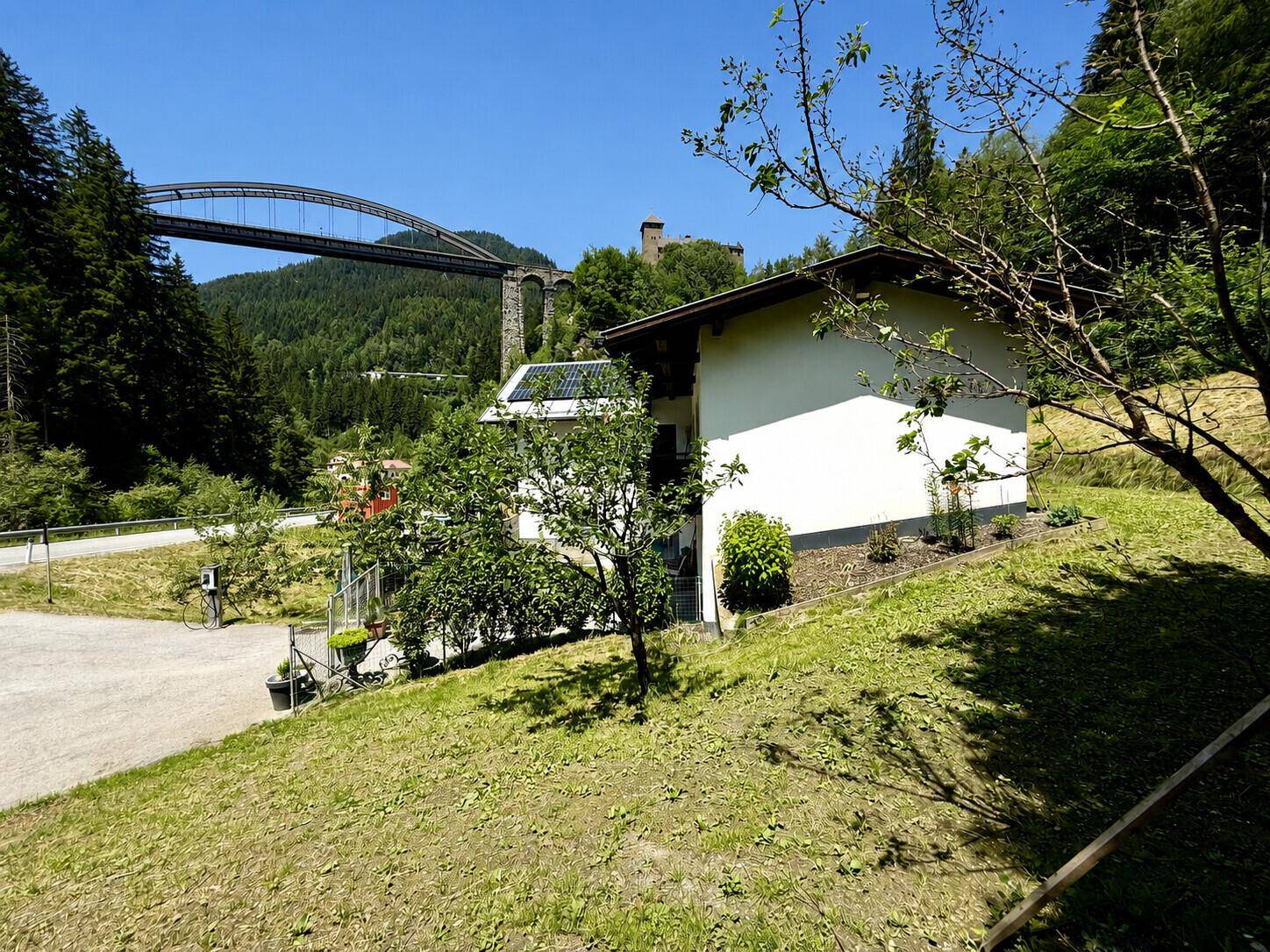 Haus in grüner Hanglage mit Blick auf eine Brücke und die umliegende Natur.
