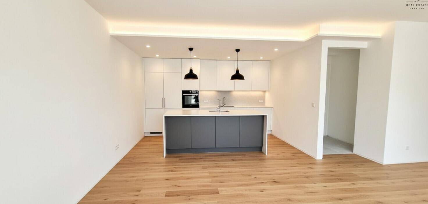Moderne offene Küche mit weißer Front, Kücheninsel und Holzboden.