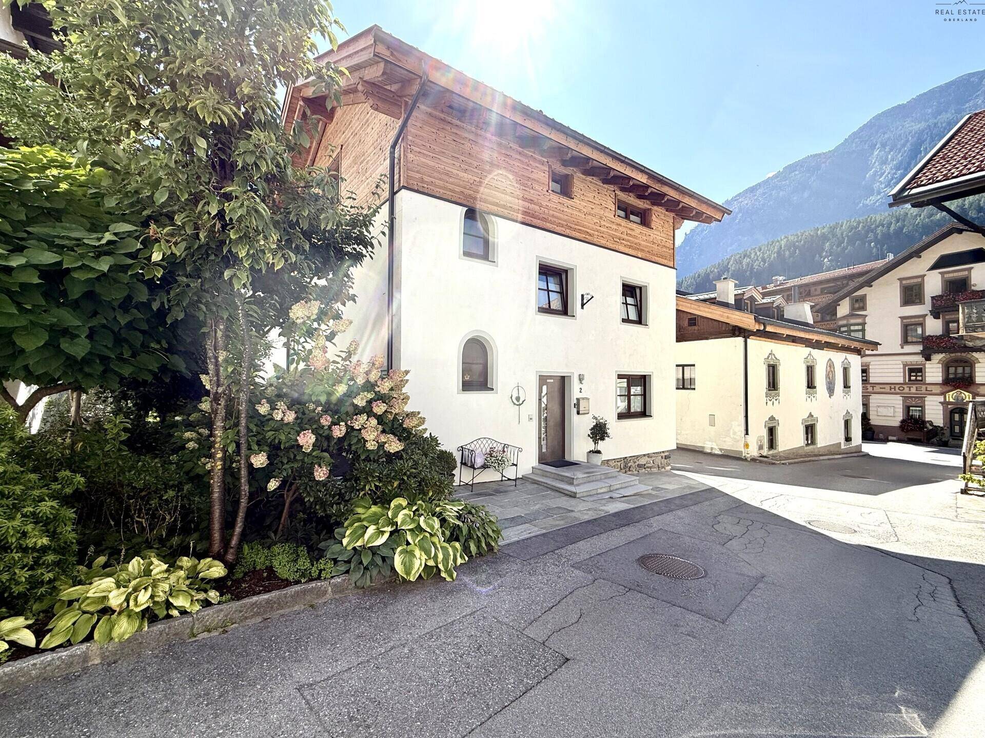 Charmantes Haus im alpinen Stil mit gepflegtem Vorgarten und Bergblick.