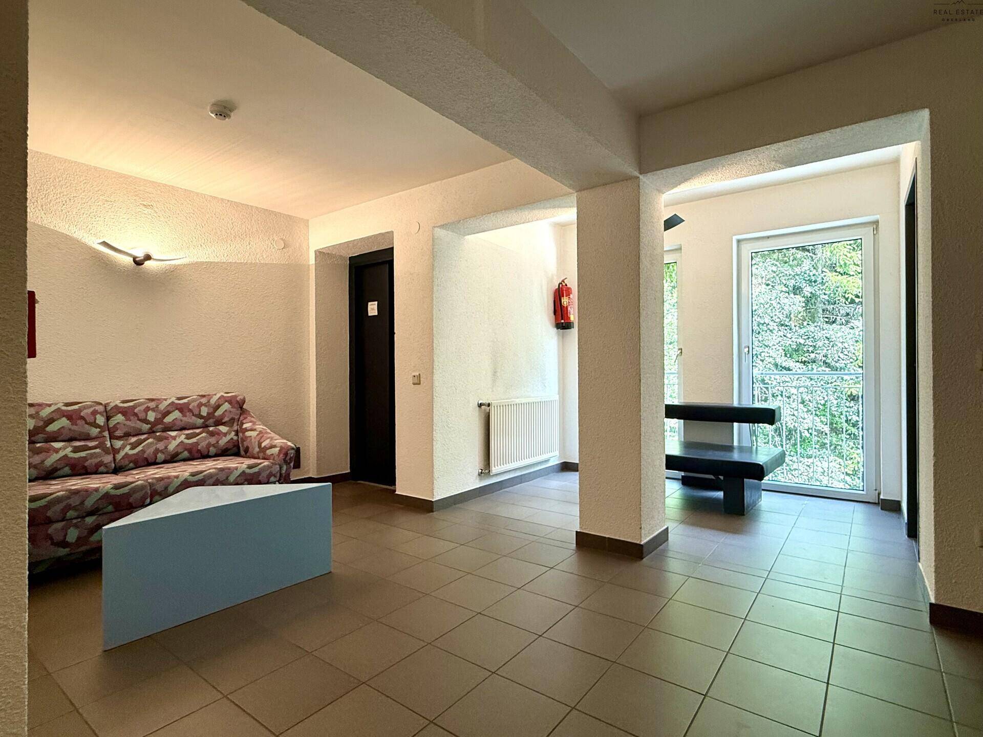 Geräumiger Eingangsbereich mit Sitzgelegenheit, Fliesenboden und Zugang zu einem Balkon.