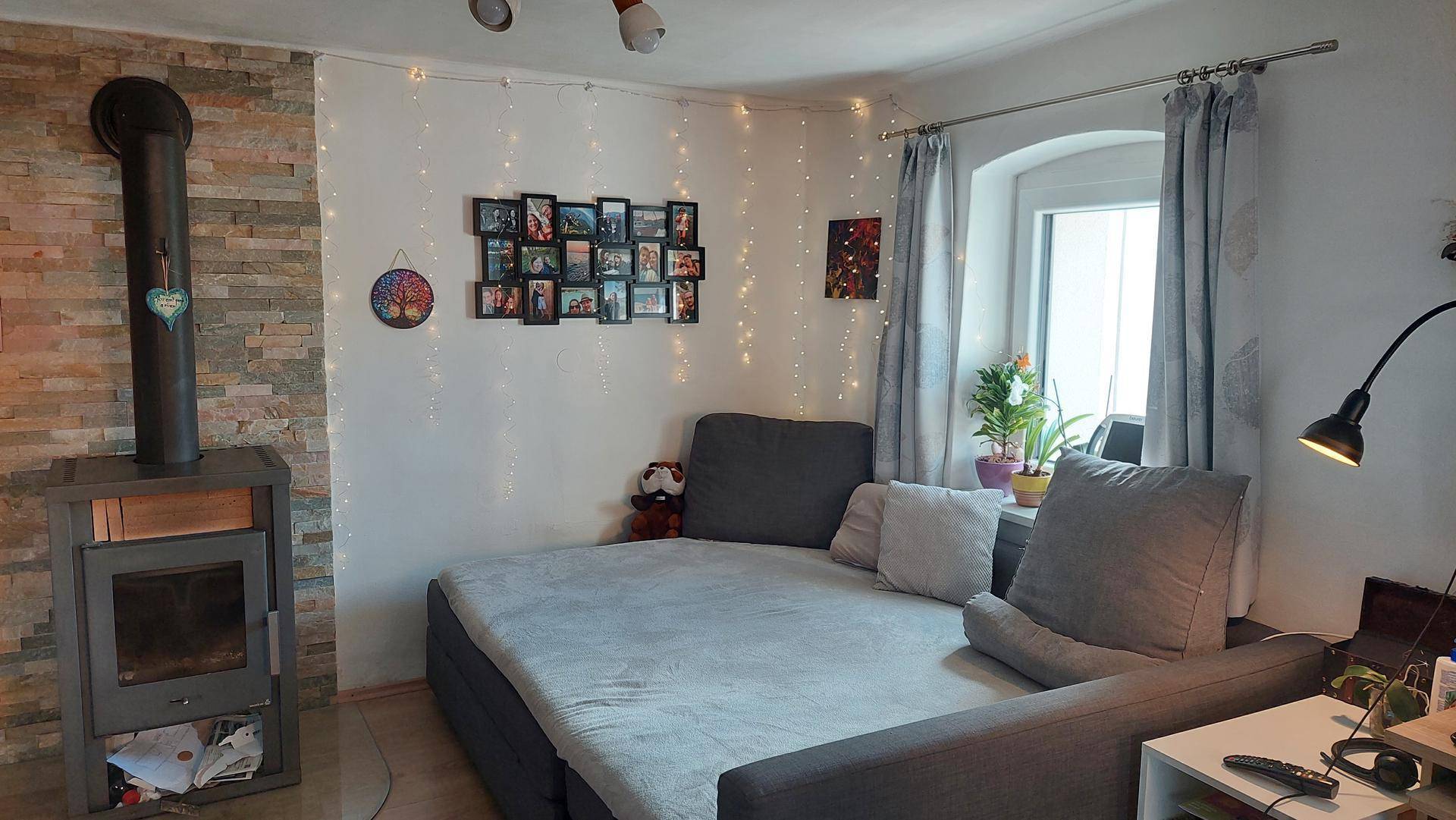 Wohnzimmer mit Kaminofen, gemütlichem Sofa und dekorativer Lichterkette.
