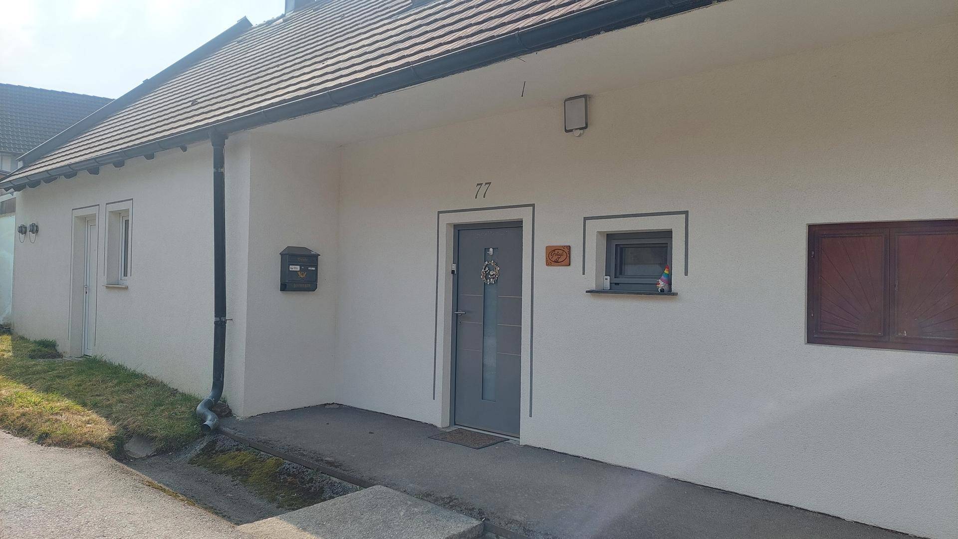 Vorderansicht eines Einfamilienhauses mit Eingangstür und Hausnummer 77.