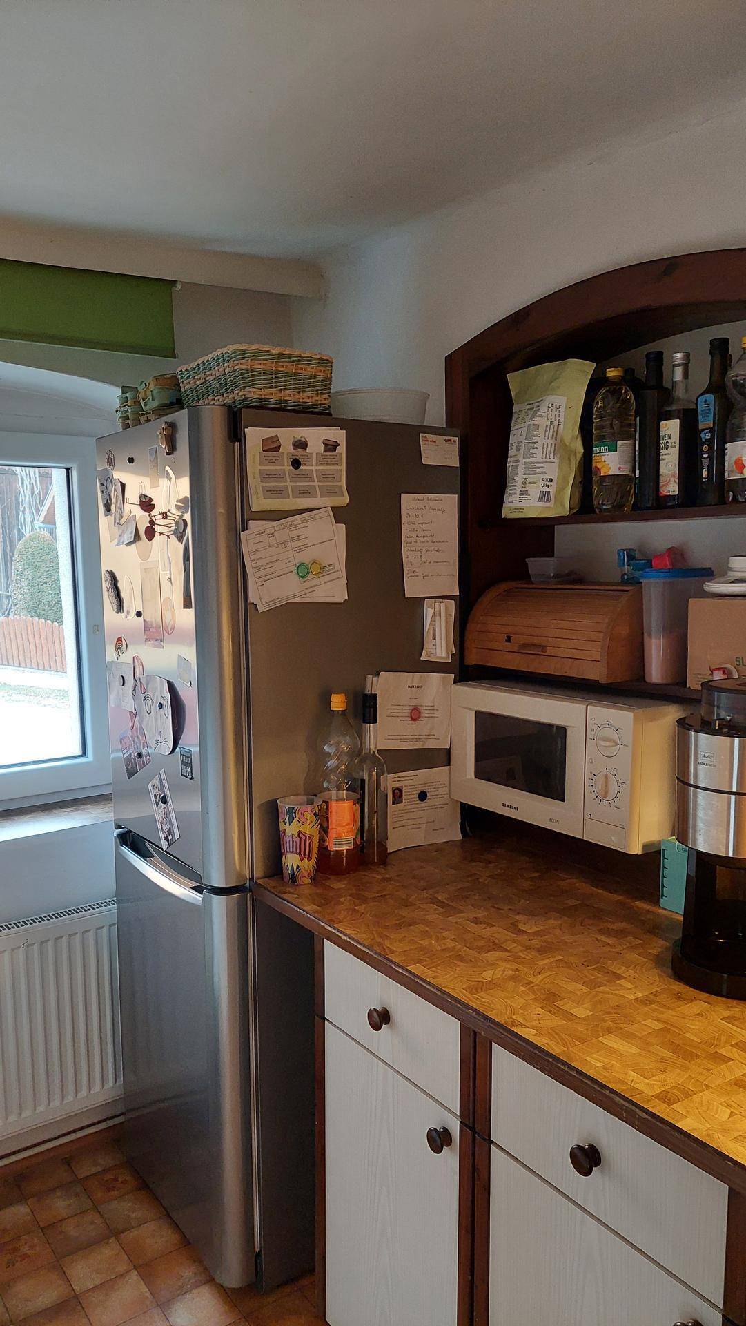 Küche mit Kühlschrank, Mikrowelle und Arbeitsplatte aus Holz.