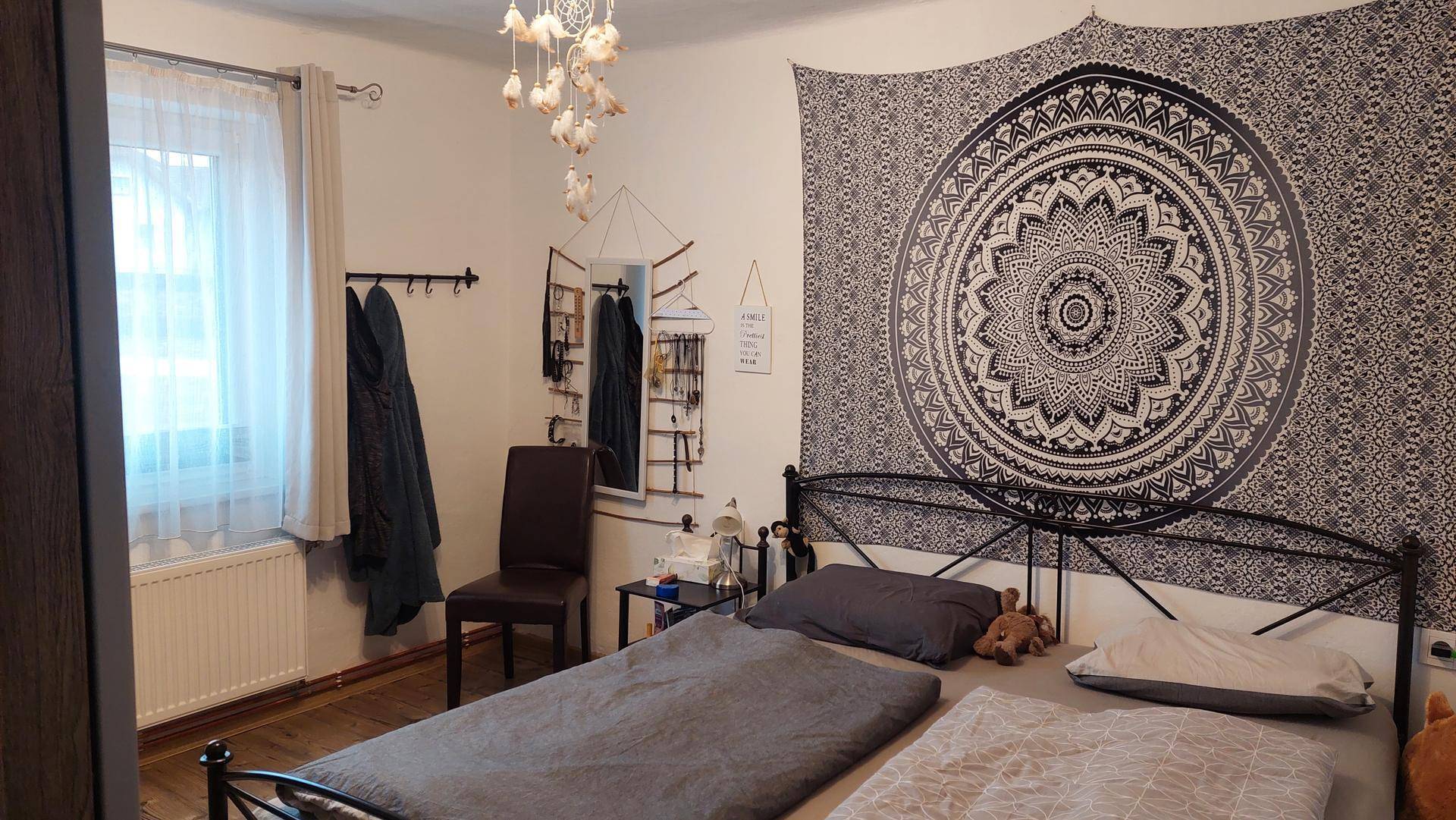Gemütliches Schlafzimmer mit Doppelbett, Wandteppich und Fenster.
