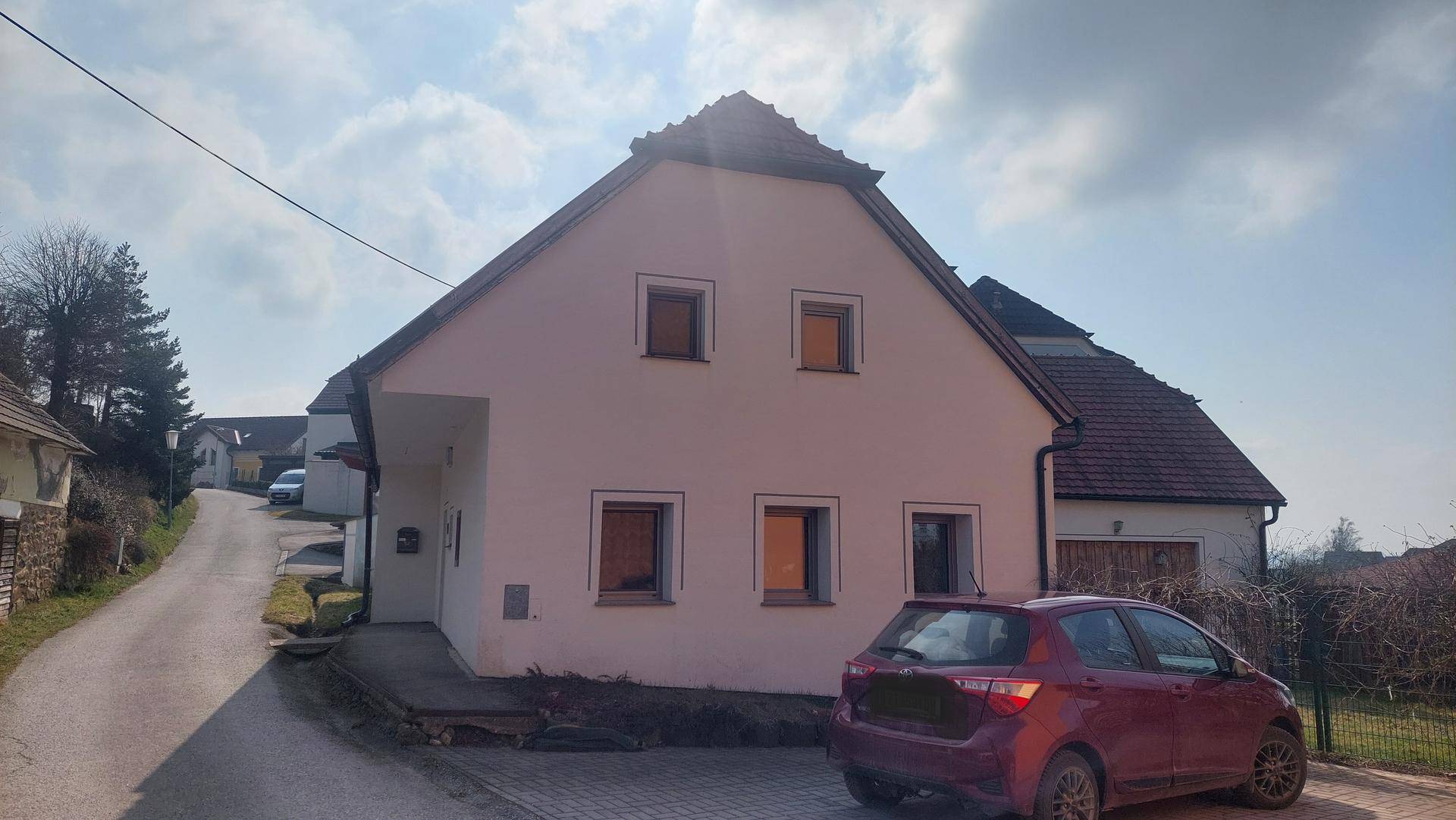 Rückansicht eines Einfamilienhauses mit Satteldach und geparktem Auto auf der Zufahrt.